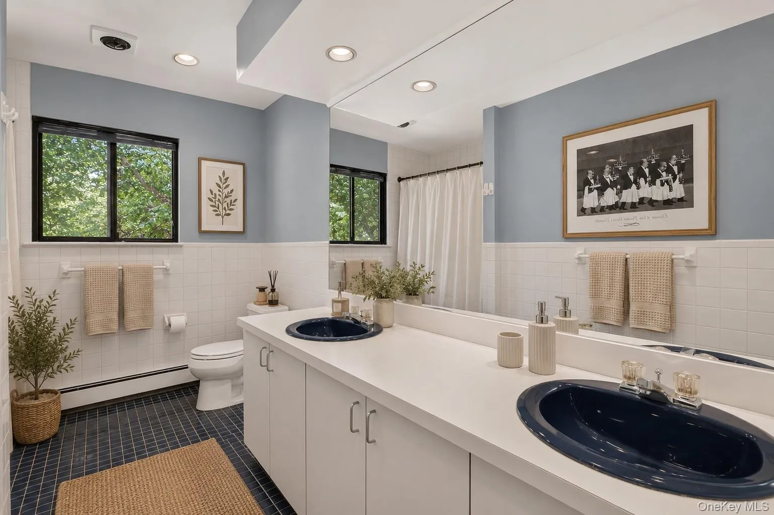 Hall bath featuring a double vanity, blue tile flooring, and a tub/shower combination. Hall bath featuring a double vanity, blue tile flooring, and a tub/shower combination.