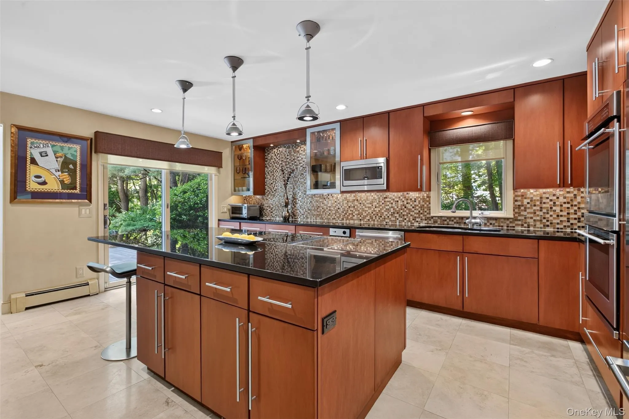 The chef's kitchen serves as the heart of the home, showcasing a center island, black granite countertops, custom cabinetry with elegant glass display accents, and a JennAir cooktop with downdraft ventilation. GE Monogram stainless steel appliances and Durango stone flooring blend timeless style with everyday functionality. The chef's kitchen serves as the heart of the home, showcasing a center island, black granite countertops, custom cabinetry with elegant glass display accents, and a JennAir cooktop with downdraft ventilation. GE Monogram stainless steel appliances and Durango stone flooring blend timeless style with everyday functionality.