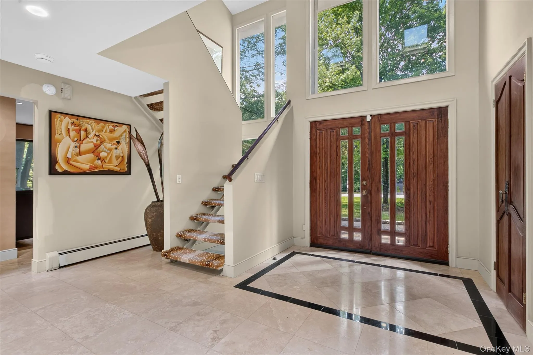 Enter through a dramatic two-story foyer featuring elegant Durango stone flooring, soaring ceilings, massive windows that flood the space with natural light, and a striking open split staircase that creates an immediate sense of grandeur and architectural interest. Enter through a dramatic two-story foyer featuring elegant Durango stone flooring, soaring ceilings, massive windows that flood the space with natural light, and a striking open split staircase that creates an immediate sense of grandeur and architectural interest.