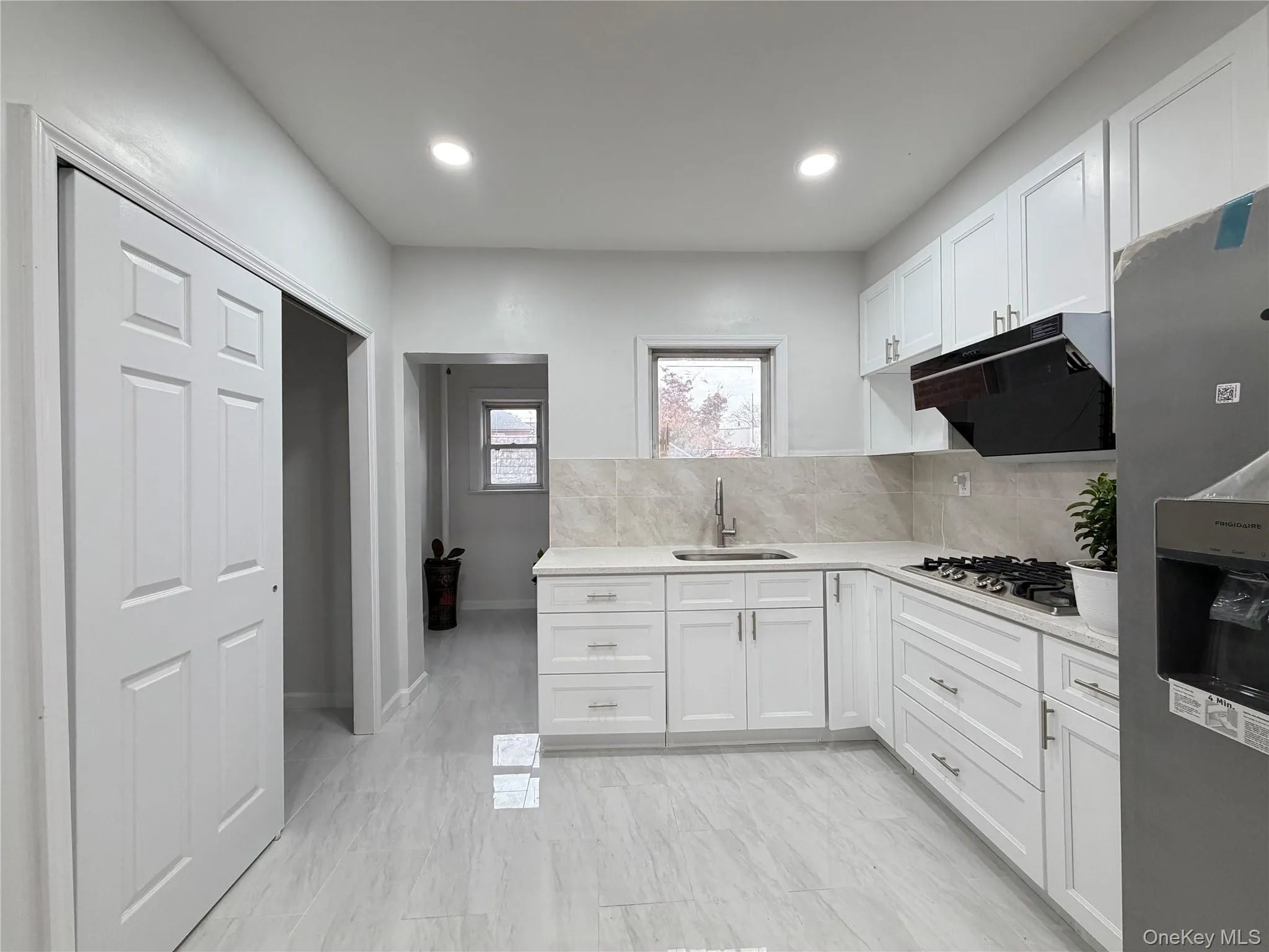 Kitchen with stainless steel appliances, white cabinets, decorative backsplash, under cabinet range hood, and light stone countertops Kitchen with stainless steel appliances, white cabinets, decorative backsplash, under cabinet range hood, and light stone countertops