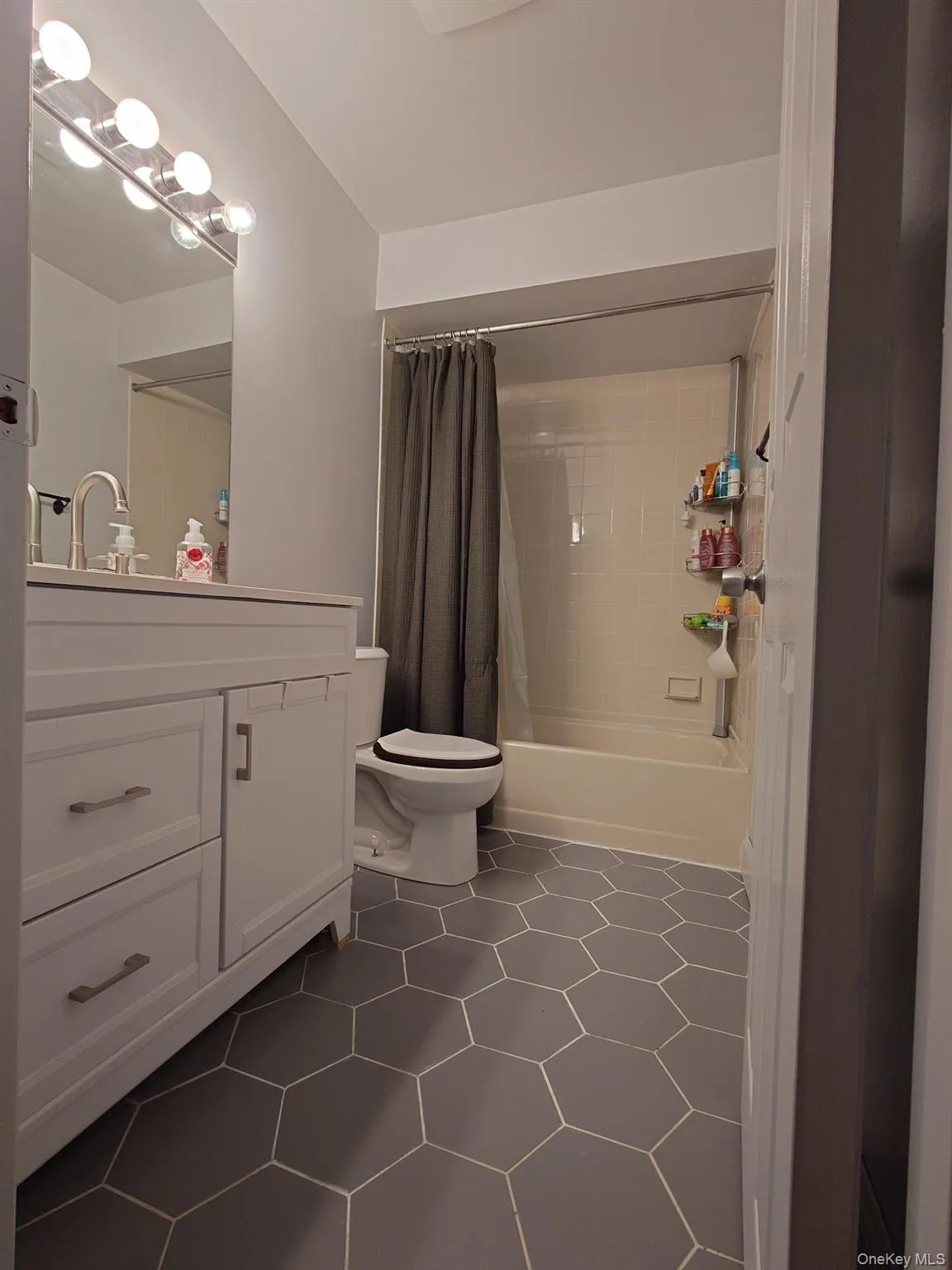 Bathroom with vanity, toilet, shower / tub combo with curtain, and tile patterned floors Bathroom with vanity, toilet, shower / tub combo with curtain, and tile patterned floors