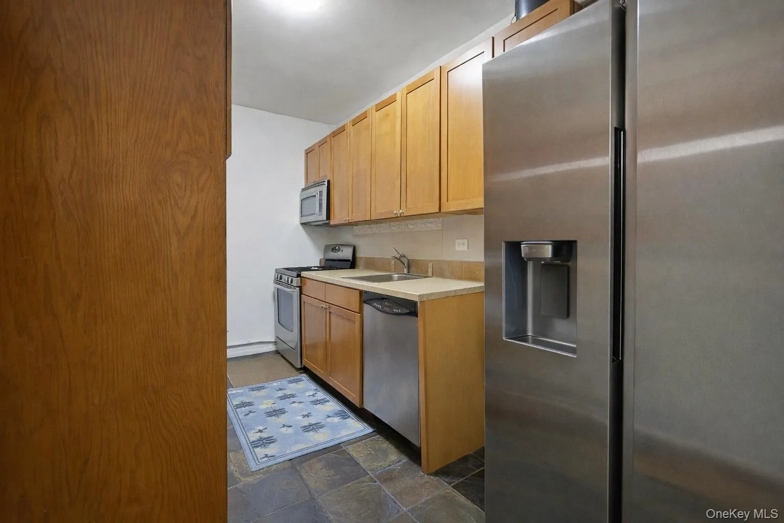 Kitchen featuring stainless steel appliances, light countertops, and stone finish flooring Kitchen featuring stainless steel appliances, light countertops, and stone finish flooring