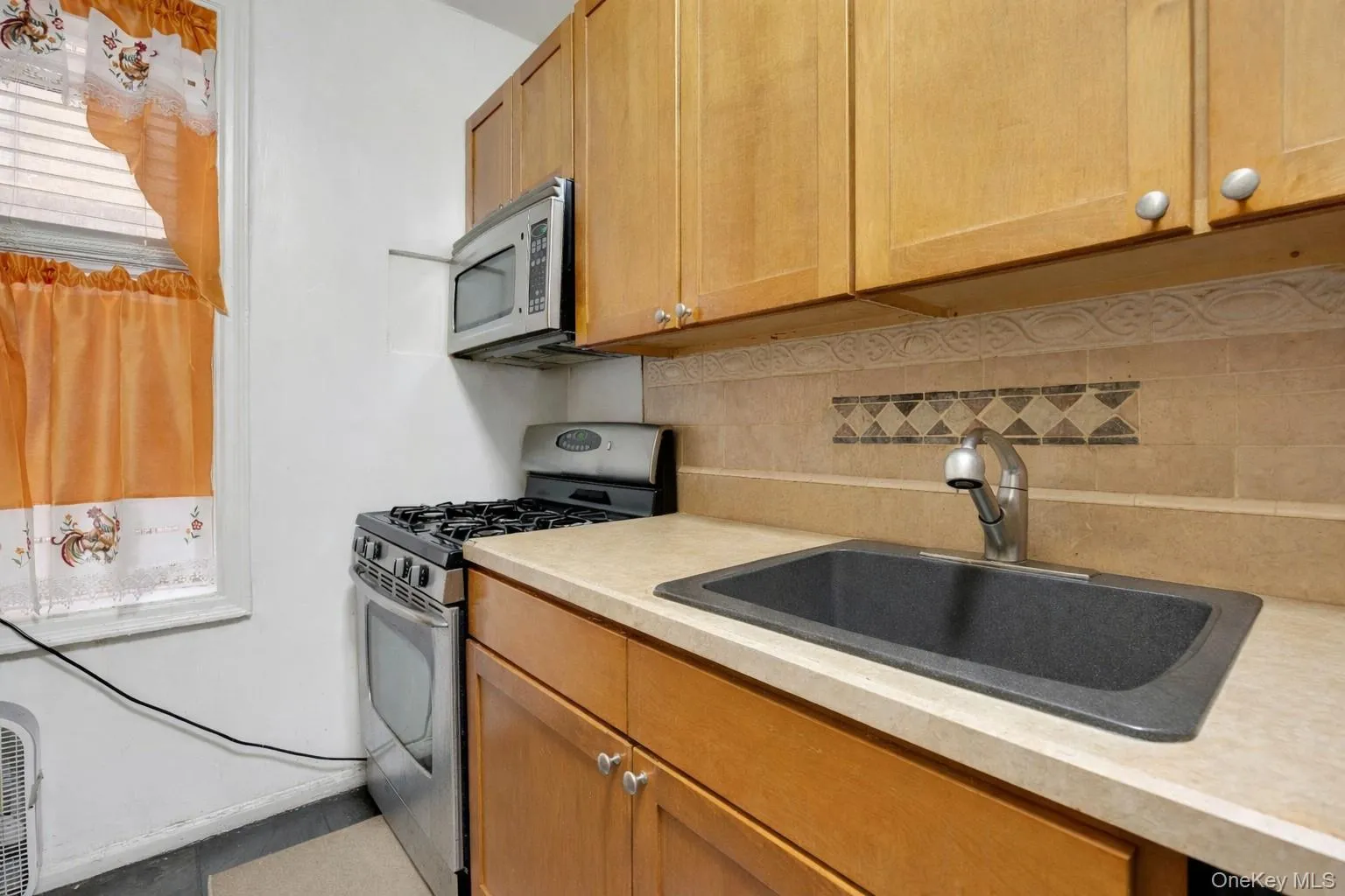 Kitchen with stainless steel appliances, backsplash, and wood finish cabinets Kitchen with stainless steel appliances, backsplash, and wood finish cabinets