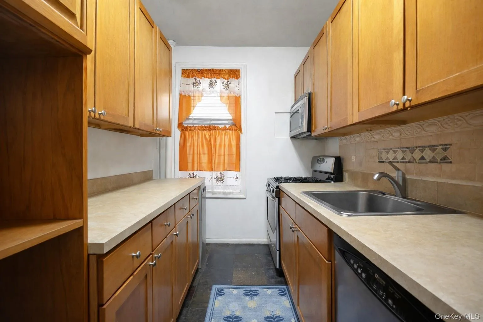 Kitchen with stainless steel appliances, light countertops, and wood finish cabinetry Kitchen with stainless steel appliances, light countertops, and wood finish cabinetry