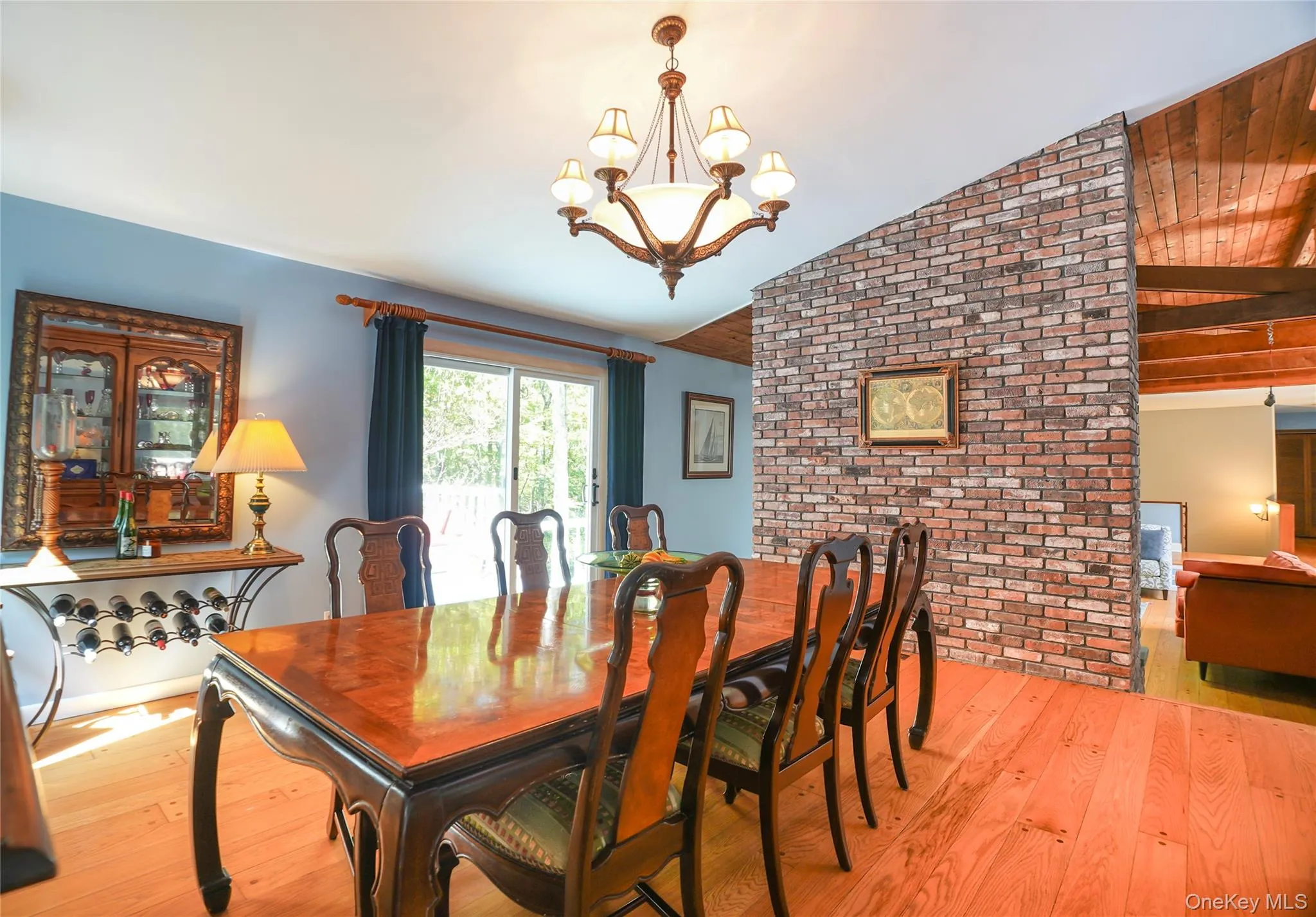 Dining area featuring light wood-finish flooring, a contemporary chandelier, and a sliding glass door Dining area featuring light wood-finish flooring, a contemporary chandelier, and a sliding glass door