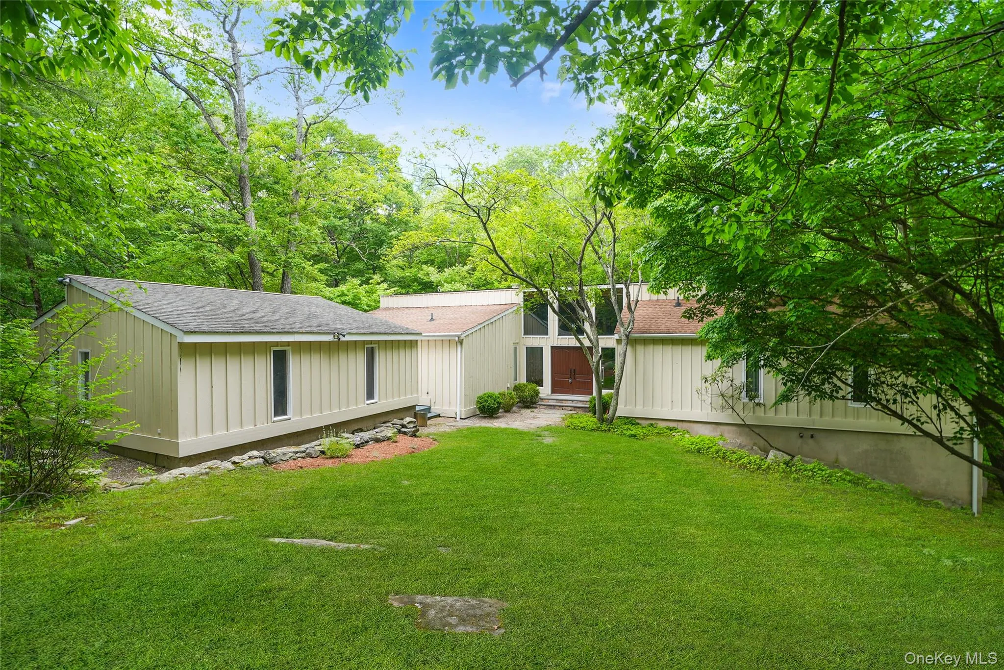 Contemporary architectural style with board and batten siding, multiple rooflines, and a prominent front entrance featuring a double door with sidelights Contemporary architectural style with board and batten siding, multiple rooflines, and a prominent front entrance featuring a double door with sidelights