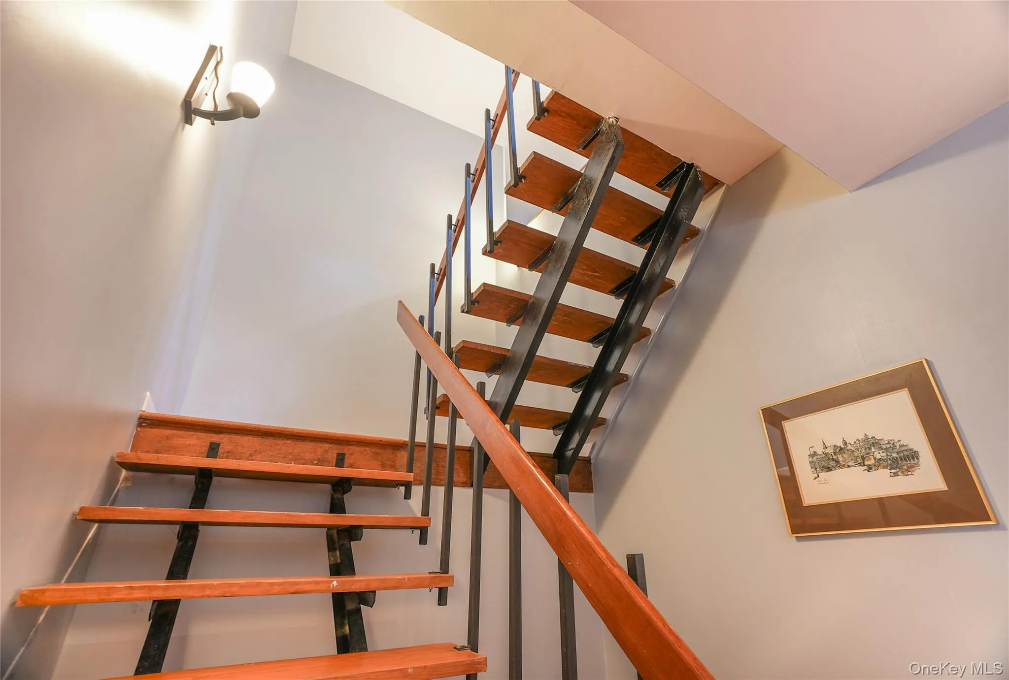 Open tread staircase featuring wood steps and a dark metal railing system Open tread staircase featuring wood steps and a dark metal railing system