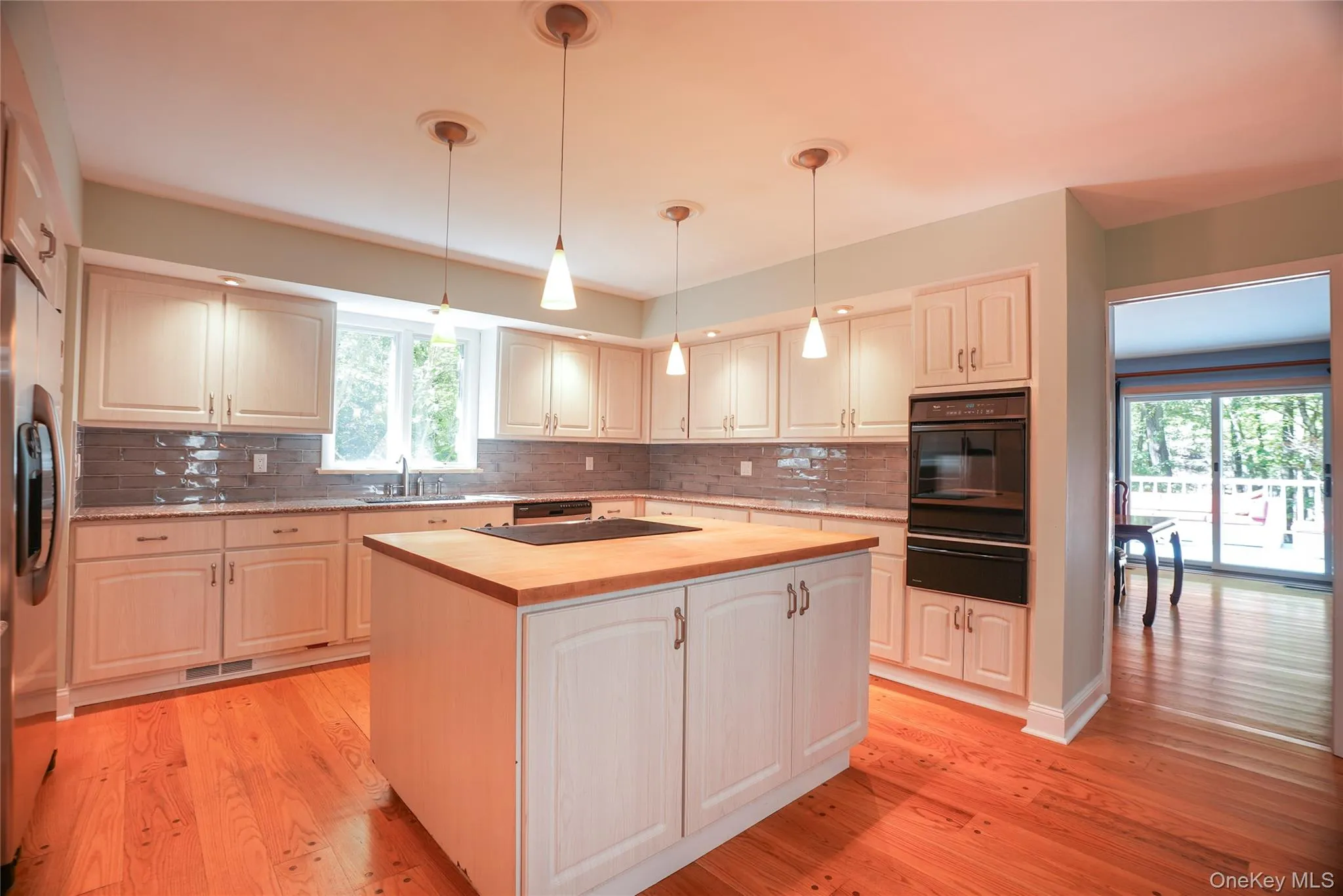 Kitchen featuring light wood cabinetry, butcher block island, stainless steel appliances, and wood-finish flooring Kitchen featuring light wood cabinetry, butcher block island, stainless steel appliances, and wood-finish flooring