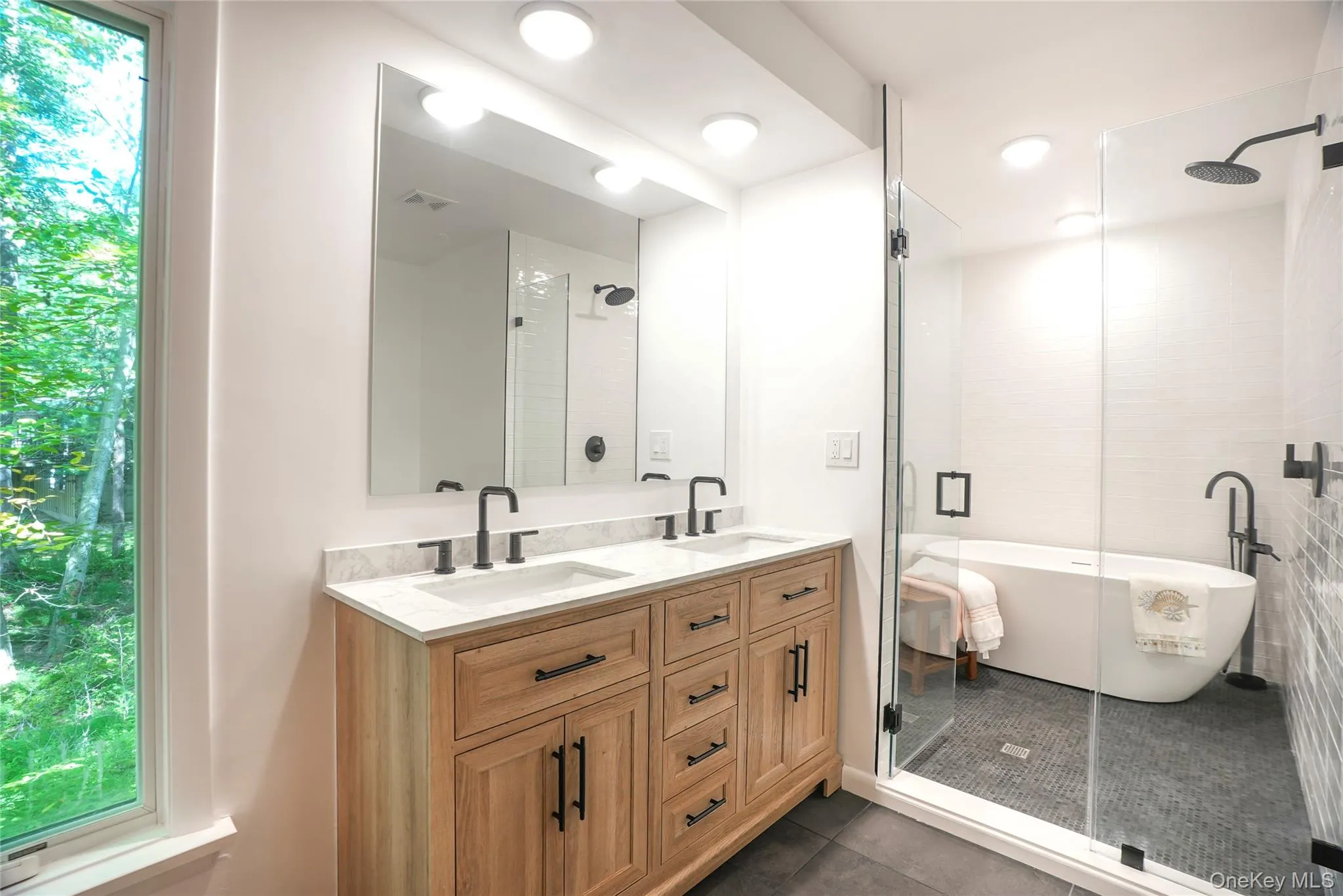 Contemporary bathroom featuring a wood-finish double vanity with stone countertops and matte black fixtures Contemporary bathroom featuring a wood-finish double vanity with stone countertops and matte black fixtures
