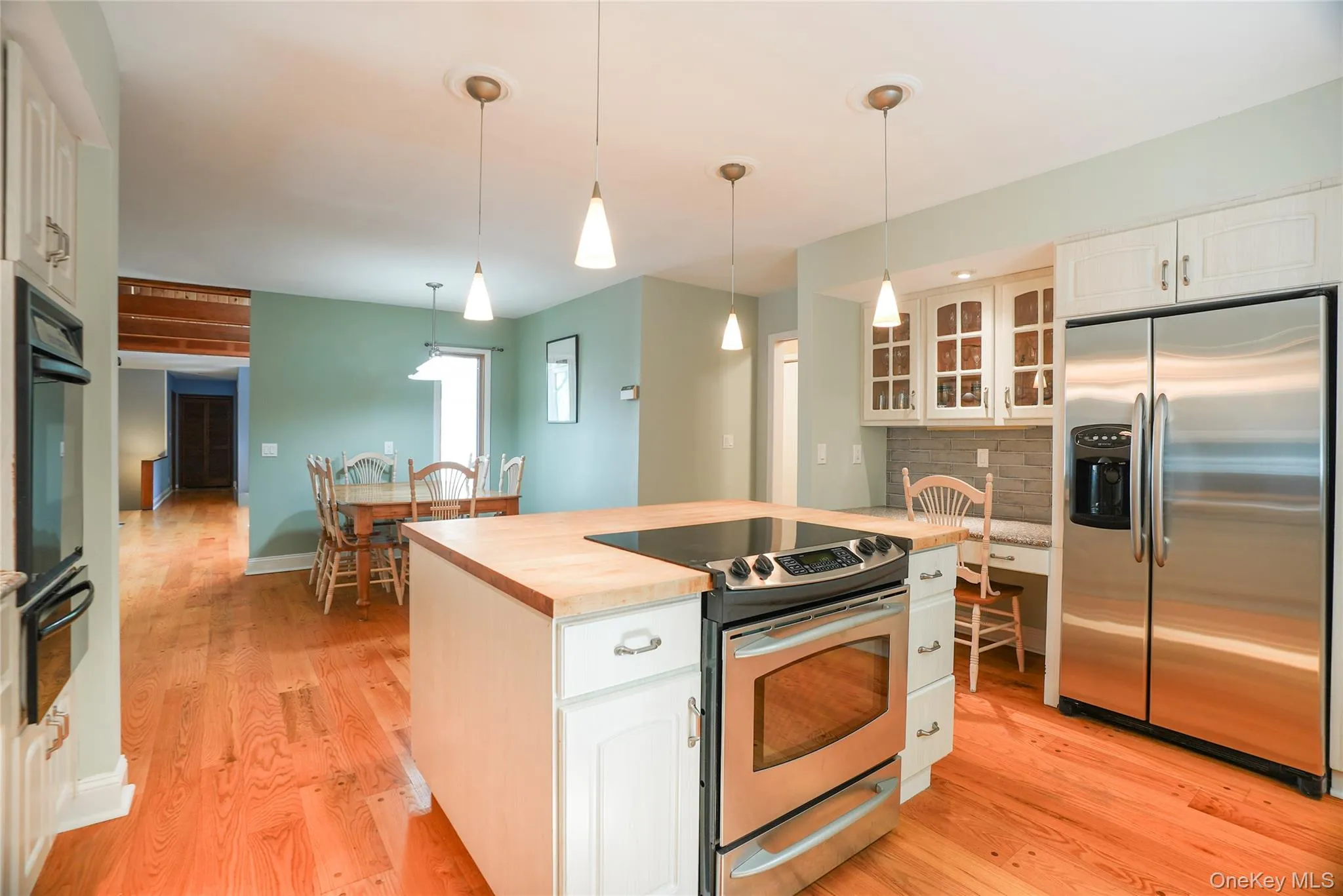 Kitchen featuring a central island with wood-finish countertop, stainless steel range, and three pendant lights Kitchen featuring a central island with wood-finish countertop, stainless steel range, and three pendant lights