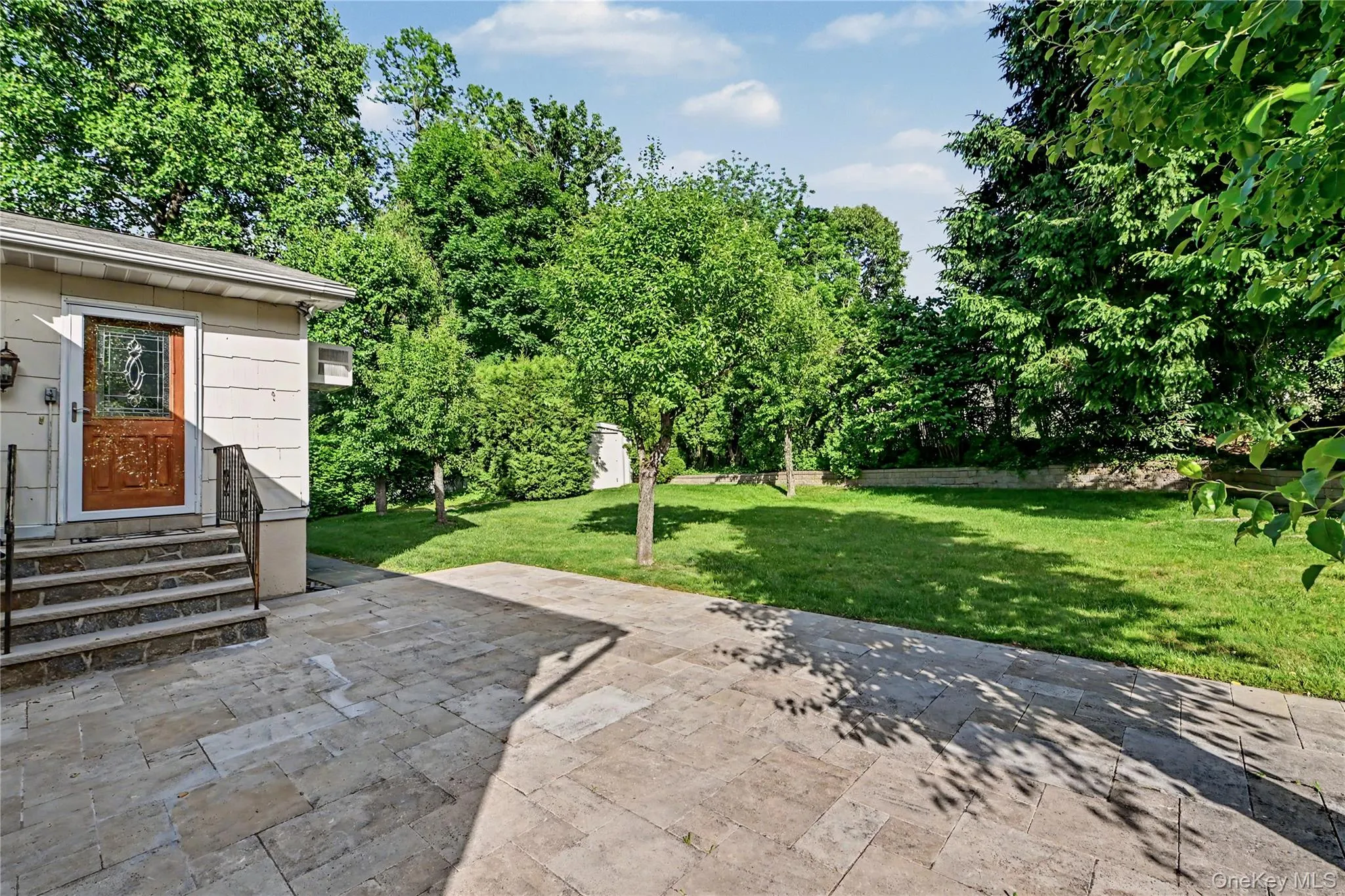 E Door from the family room leads out to an expansive patio with stone pavers, leading to a sprawling lawn surrounded by mature trees E Door from the family room leads out to an expansive patio with stone pavers, leading to a sprawling lawn surrounded by mature trees
