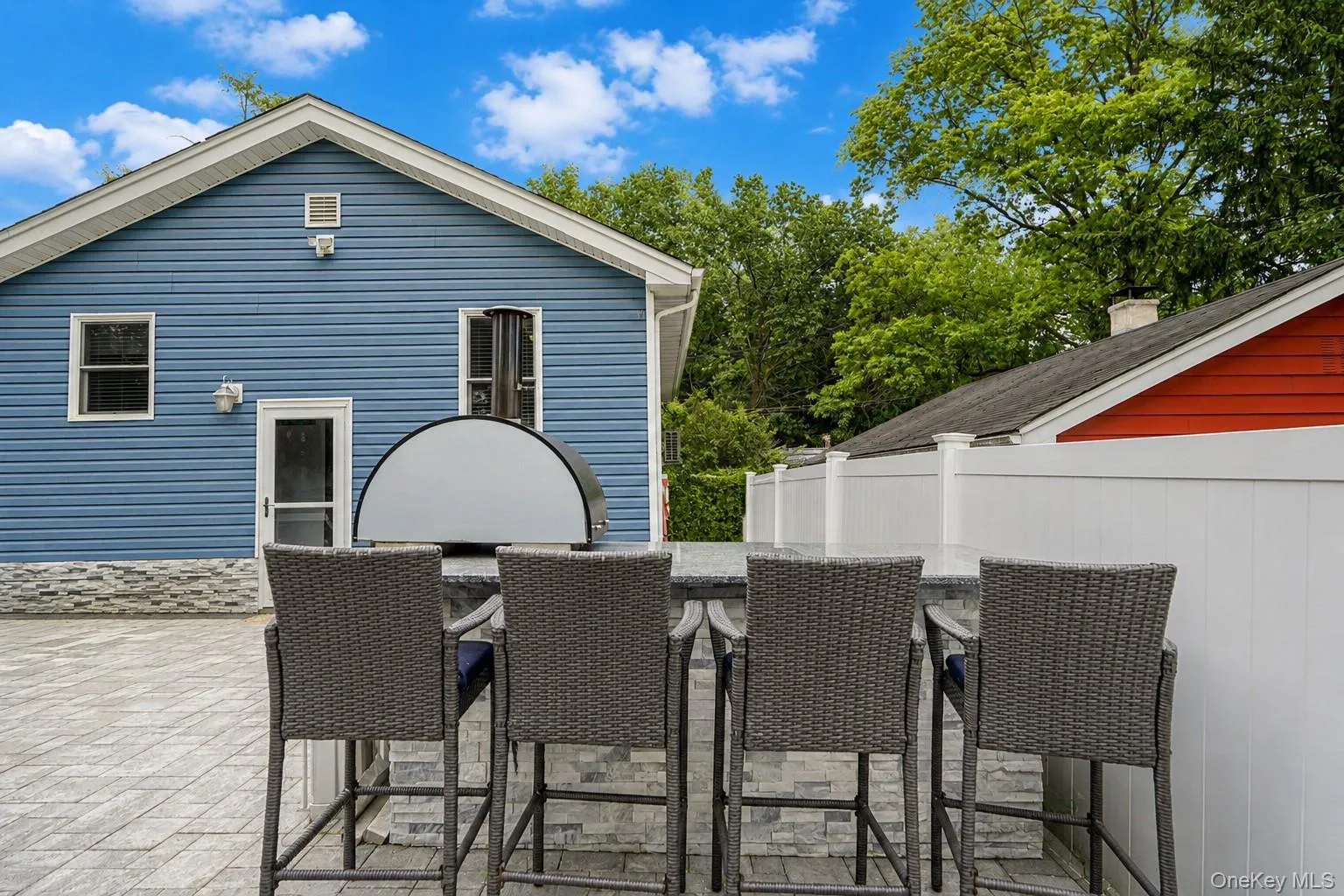 Patio features a built-in outdoor kitchen with a stone-finish base and a light-colored countertop, complemented by a paver patio surface Patio features a built-in outdoor kitchen with a stone-finish base and a light-colored countertop, complemented by a paver patio surface