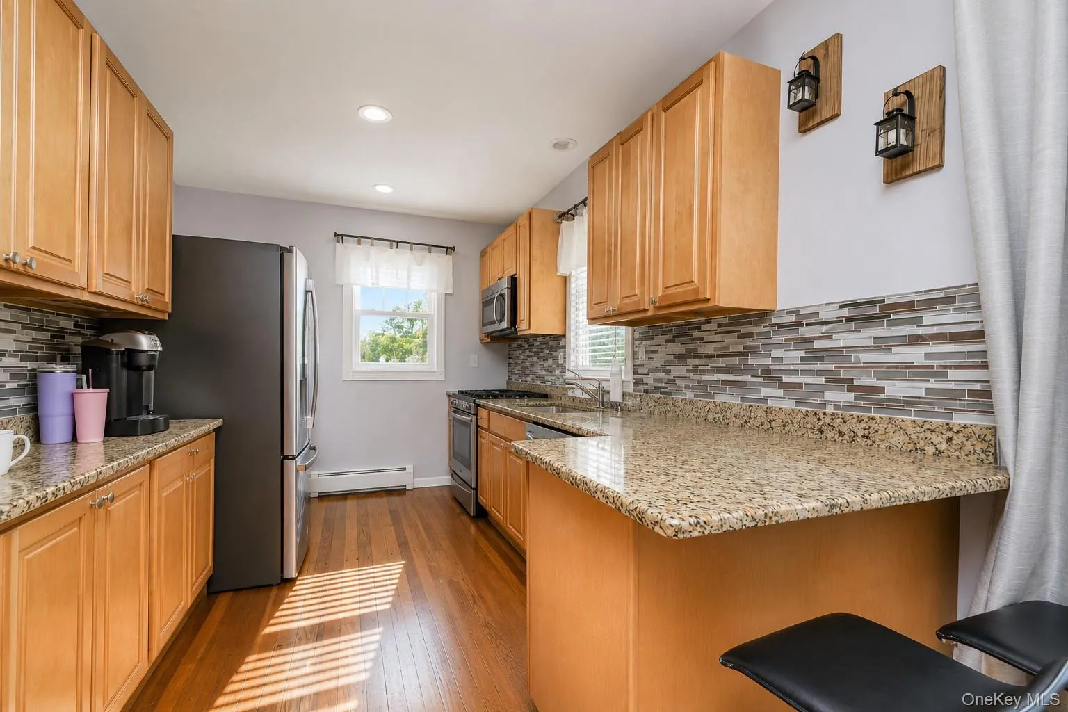 Kitchen featuring wood-finish flooring, light wood cabinetry, and speckled countertops Kitchen featuring wood-finish flooring, light wood cabinetry, and speckled countertops