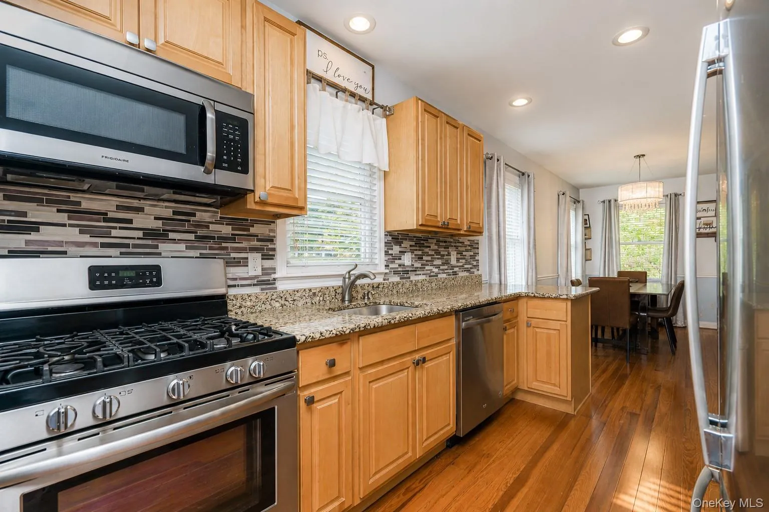Kitchen featuring stainless steel appliances, light wood cabinetry, a mosaic tile backsplash, and granite countertops Kitchen featuring stainless steel appliances, light wood cabinetry, a mosaic tile backsplash, and granite countertops