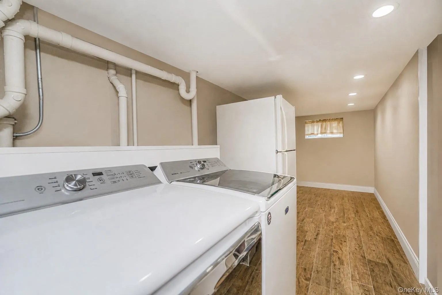Laundry area featuring a side-by-side washer and dryer, recessed ceiling lighting, and wood-finish flooring Laundry area featuring a side-by-side washer and dryer, recessed ceiling lighting, and wood-finish flooring