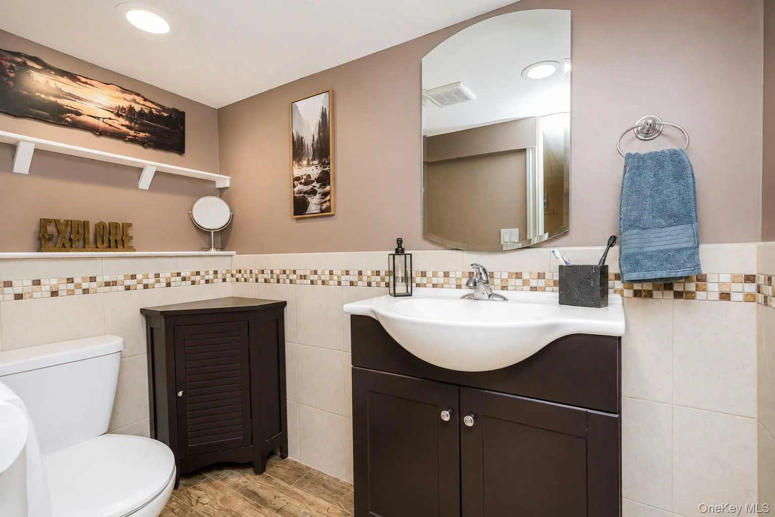 Bathroom featuring a dark wood-finish vanity with a white integrated sink, chrome faucet, and an arched wall mirror Bathroom featuring a dark wood-finish vanity with a white integrated sink, chrome faucet, and an arched wall mirror
