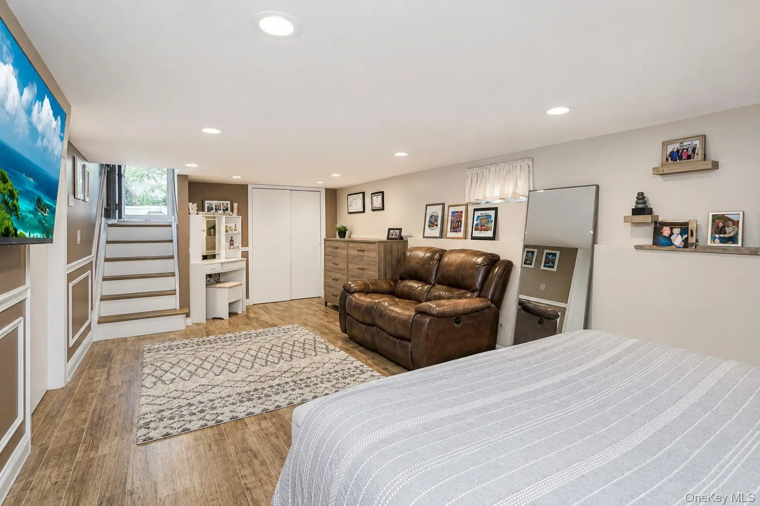 Finished lower level featuring wood-finish flooring, recessed lighting, a white painted staircase with wood treads, and white bi-fold closet doors Finished lower level featuring wood-finish flooring, recessed lighting, a white painted staircase with wood treads, and white bi-fold closet doors