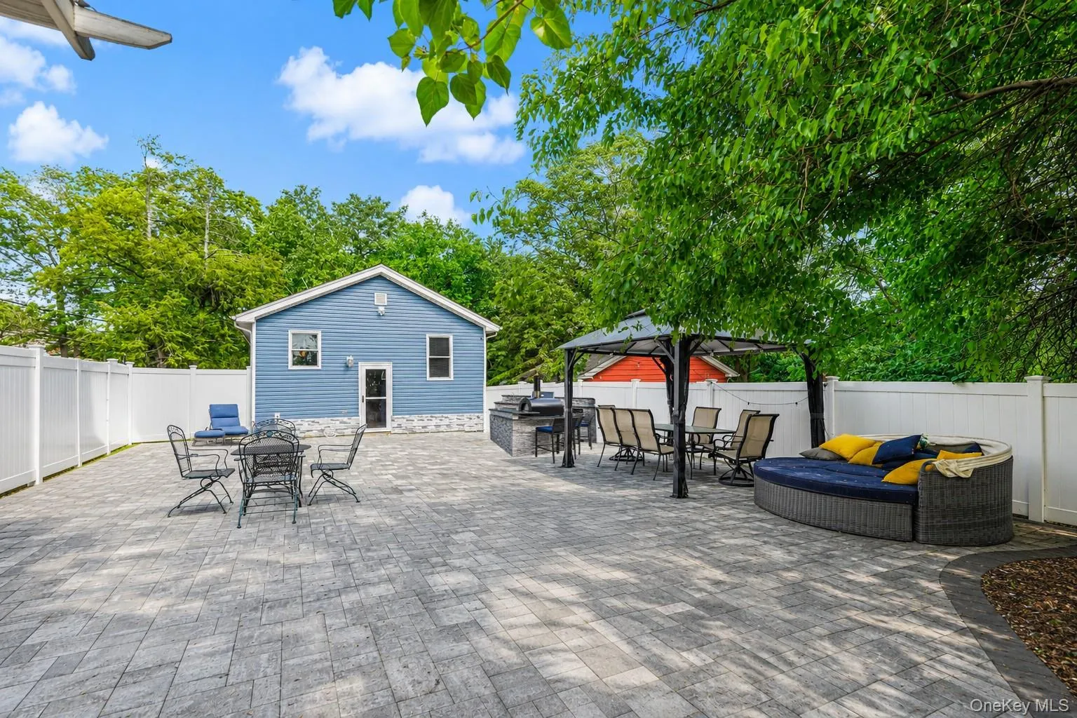 Expansive paver patio bordered by a white vinyl fence Expansive paver patio bordered by a white vinyl fence