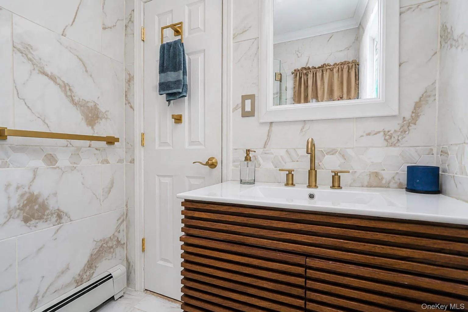 Bathroom vanity featuring a wood-finish slatted cabinet, integrated sink, and gold-finish fixtures Bathroom vanity featuring a wood-finish slatted cabinet, integrated sink, and gold-finish fixtures