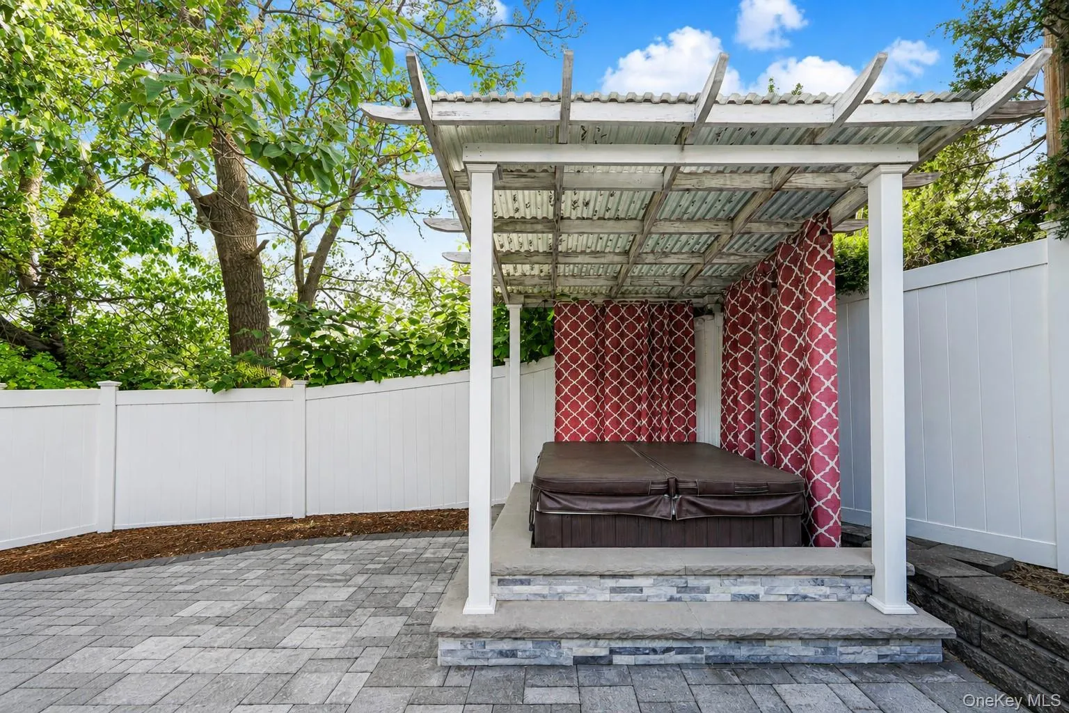 Paved patio area featuring a covered spa structure with privacy curtains Paved patio area featuring a covered spa structure with privacy curtains