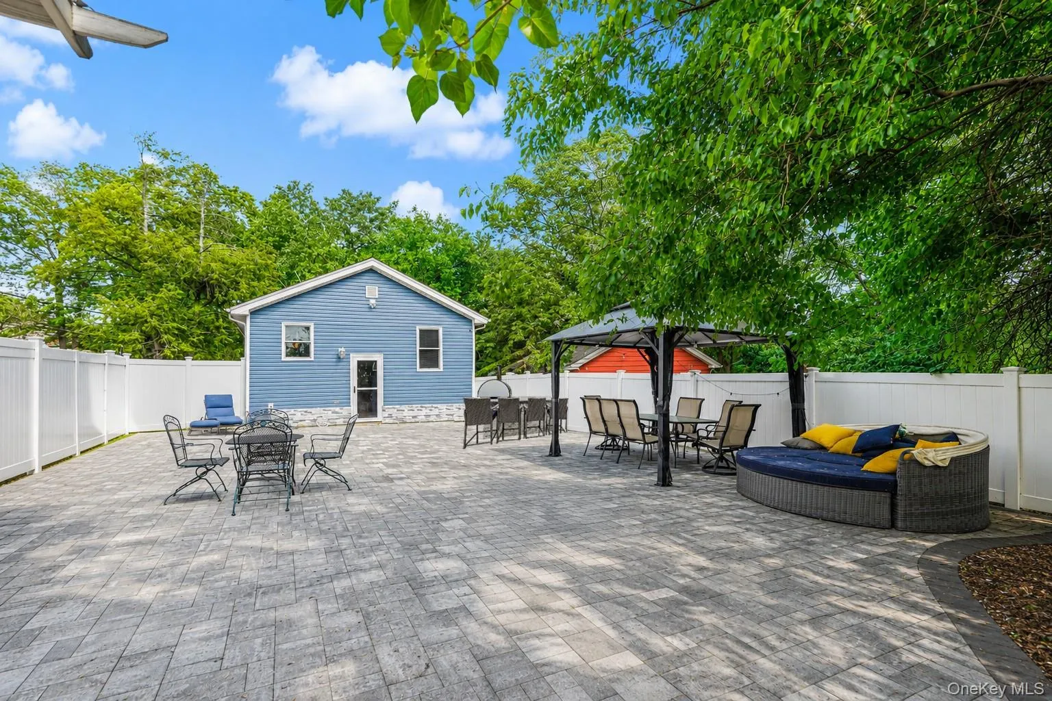 Spacious paver patio with a white privacy fence and mature trees Spacious paver patio with a white privacy fence and mature trees