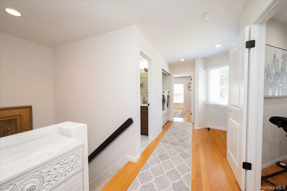 Hardwood flooring throughout the hallway, recessed lighting, and white paneled doors with black hardware Hardwood flooring throughout the hallway, recessed lighting, and white paneled doors with black hardware