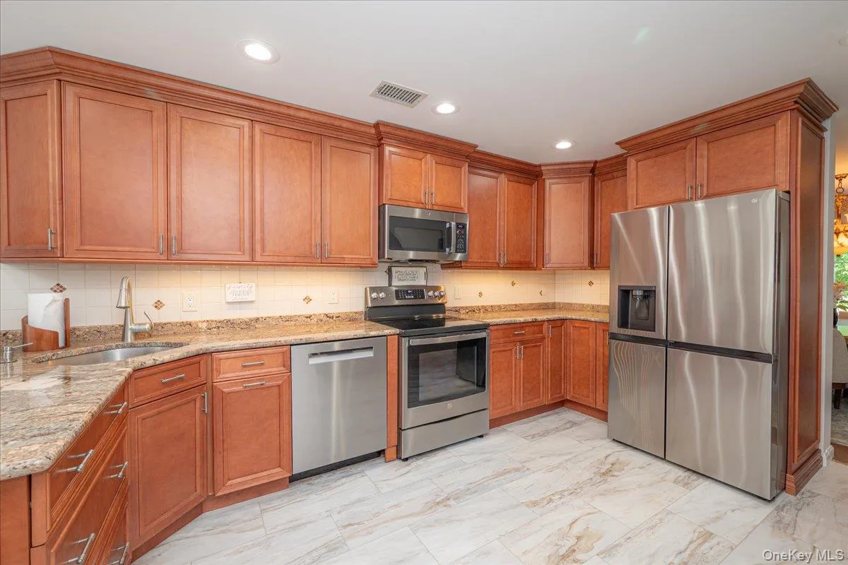 Kitchen featuring wood cabinetry, granite countertops, stainless steel appliances, tile flooring, and recessed lighting Kitchen featuring wood cabinetry, granite countertops, stainless steel appliances, tile flooring, and recessed lighting