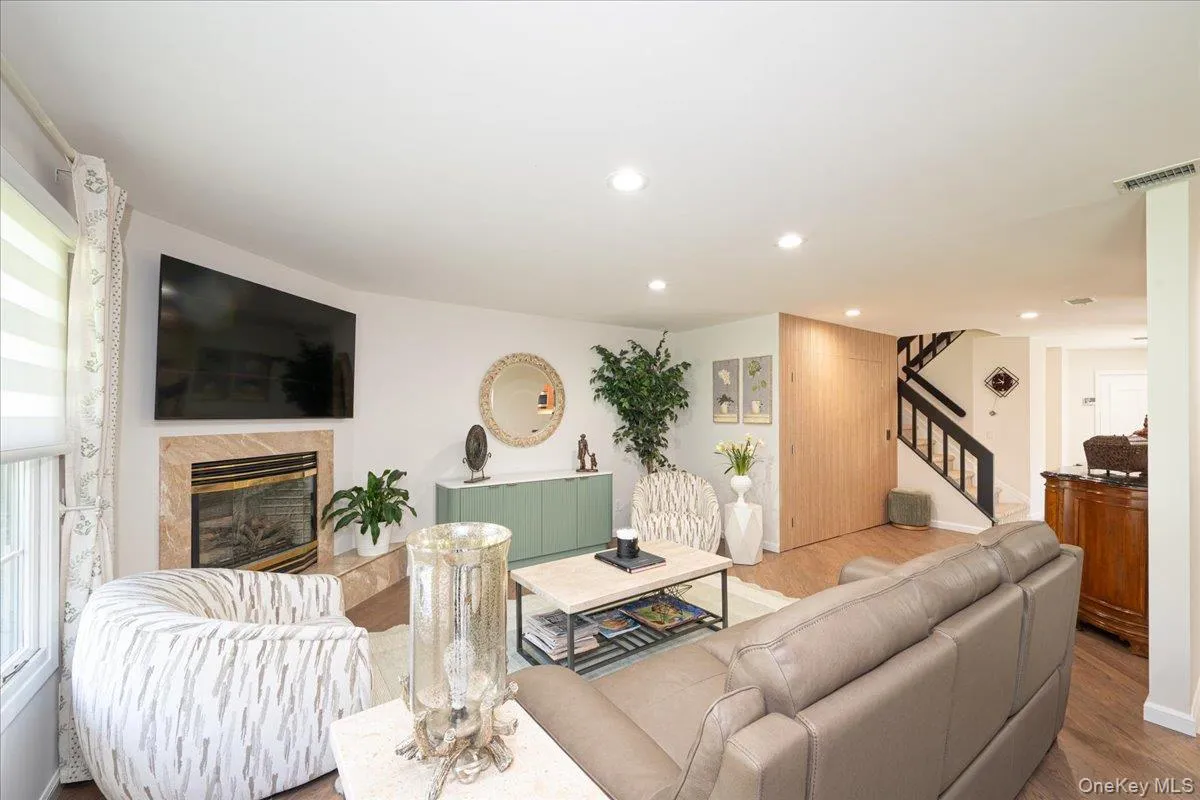 Living area featuring a fireplace with a stone surround, recessed lighting, and wood-finish flooring Living area featuring a fireplace with a stone surround, recessed lighting, and wood-finish flooring