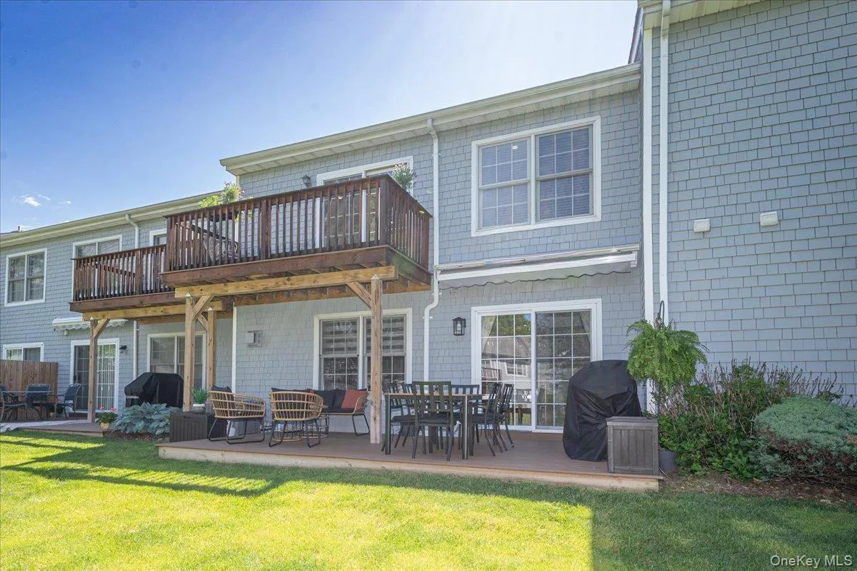 Rear exterior featuring gray shake siding, a ground-level patio, and an upper-level wood deck Rear exterior featuring gray shake siding, a ground-level patio, and an upper-level wood deck