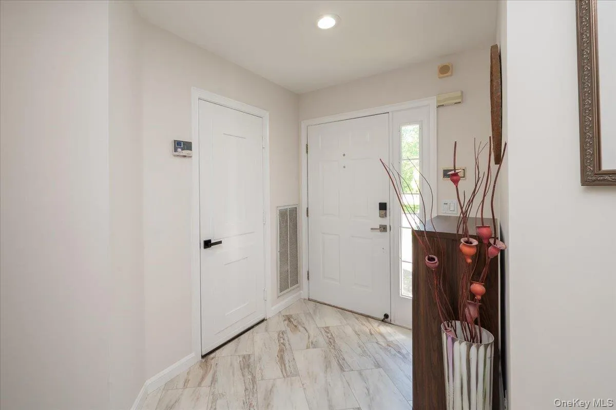 Entryway featuring wood-finish tile flooring, recessed lighting, and a white paneled door with matte black hardware Entryway featuring wood-finish tile flooring, recessed lighting, and a white paneled door with matte black hardware