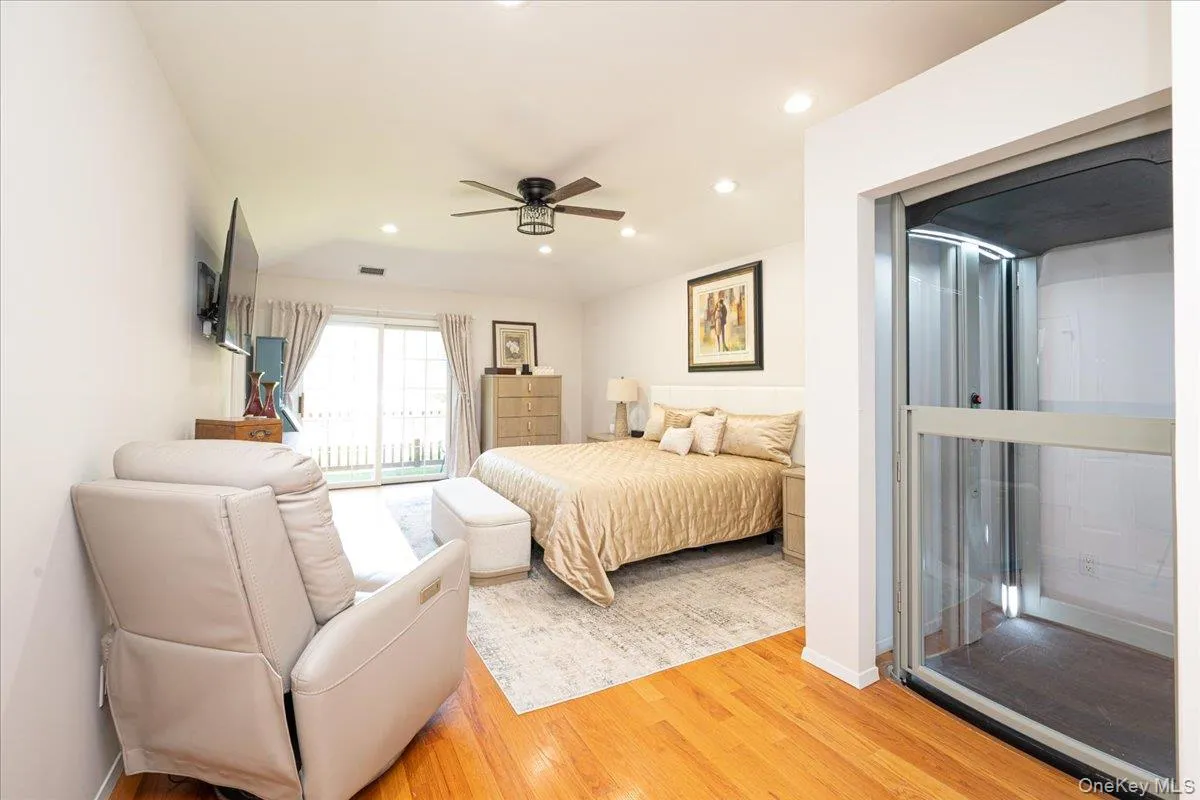 Bedroom featuring hardwood flooring, recessed lighting, a ceiling fan, a sliding glass door to an outdoor area, and a built-in glass-enclosed elevator Bedroom featuring hardwood flooring, recessed lighting, a ceiling fan, a sliding glass door to an outdoor area, and a built-in glass-enclosed elevator
