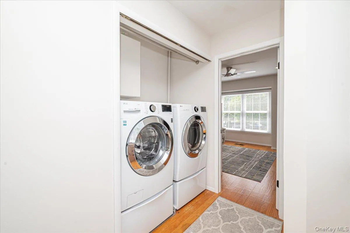 Dedicated laundry area featuring a front-loading washer and dryer, integrated storage cabinet, and a chrome hanging rod Dedicated laundry area featuring a front-loading washer and dryer, integrated storage cabinet, and a chrome hanging rod