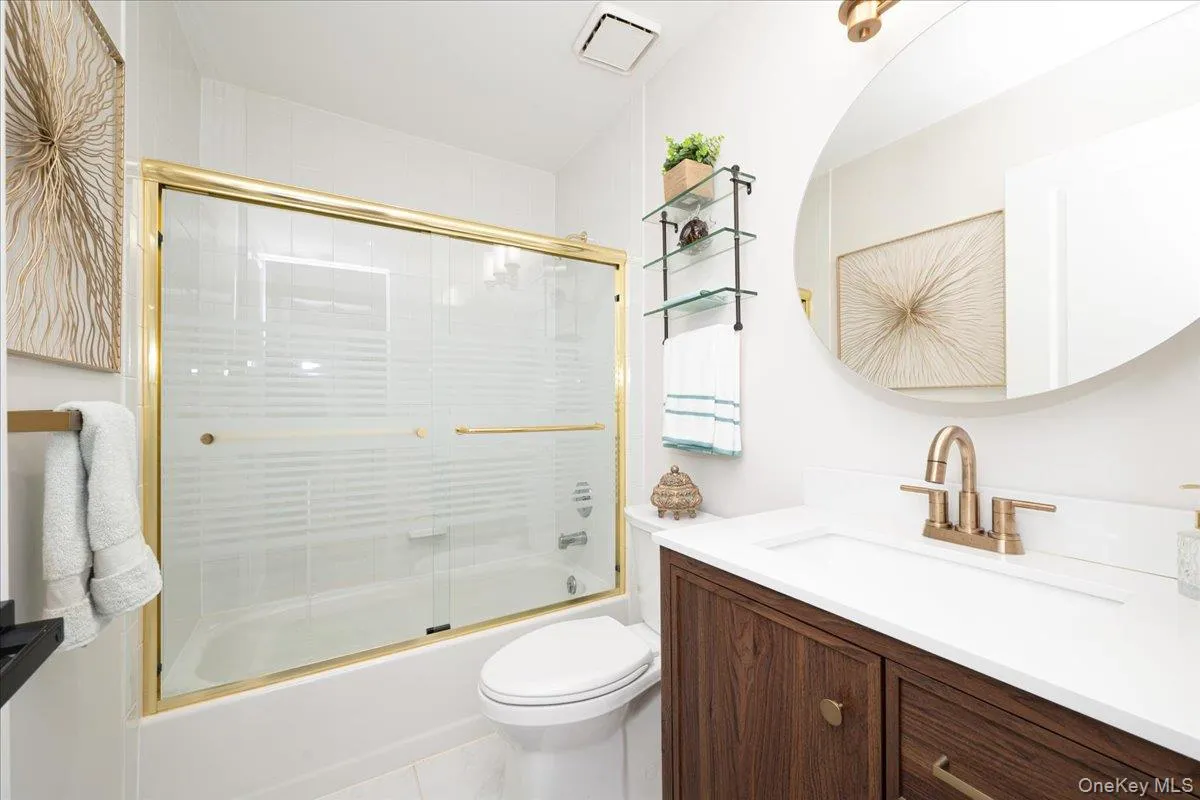 Bathroom with a gold-framed shower enclosure, white tub, and white wall tiles Bathroom with a gold-framed shower enclosure, white tub, and white wall tiles