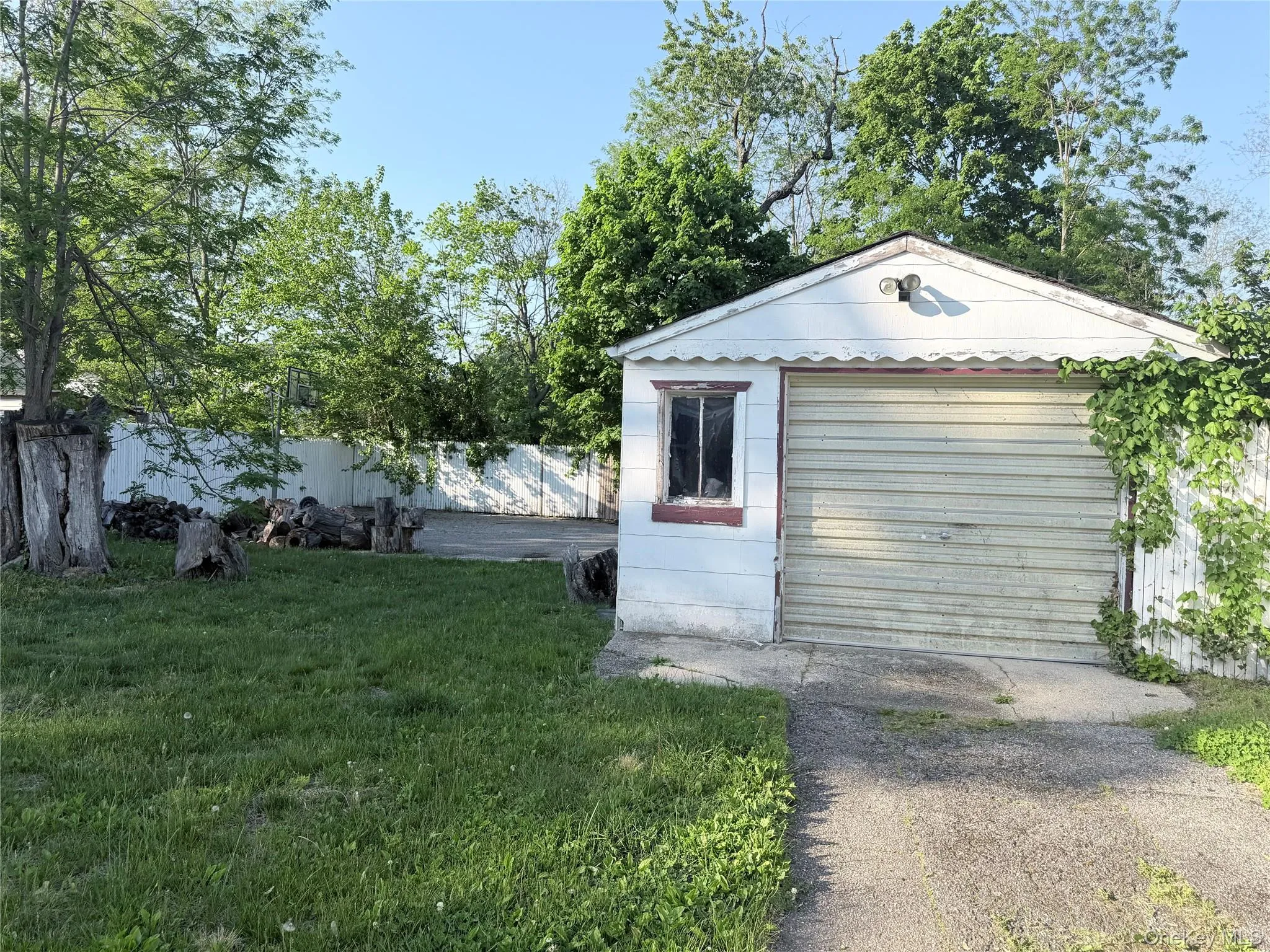 Detached garage structure featuring a roll-up door and a single-pane window Detached garage structure featuring a roll-up door and a single-pane window