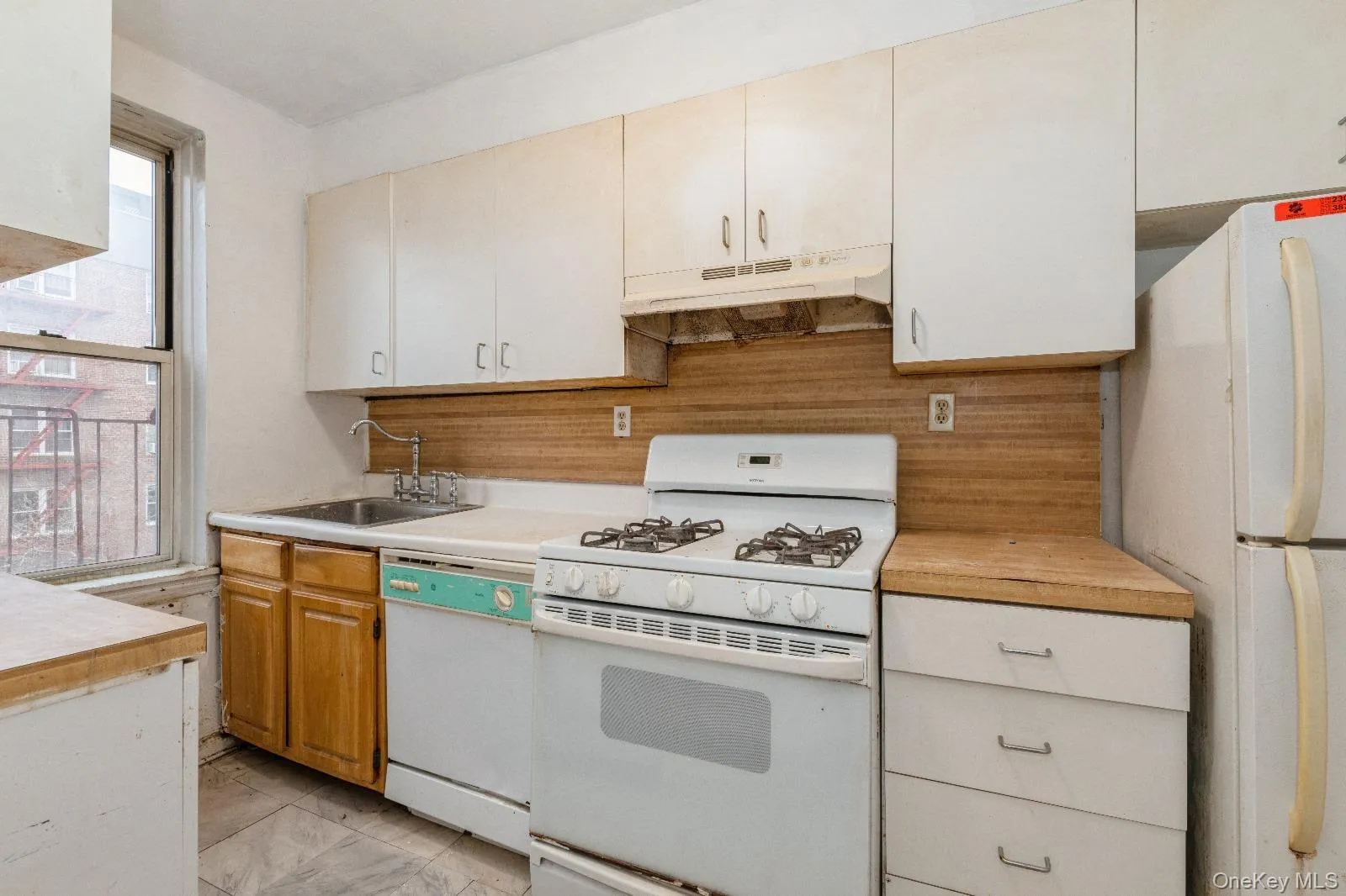 Kitchen featuring light countertops, a sink, under cabinet range hood, and white appliances Kitchen featuring light countertops, a sink, under cabinet range hood, and white appliances