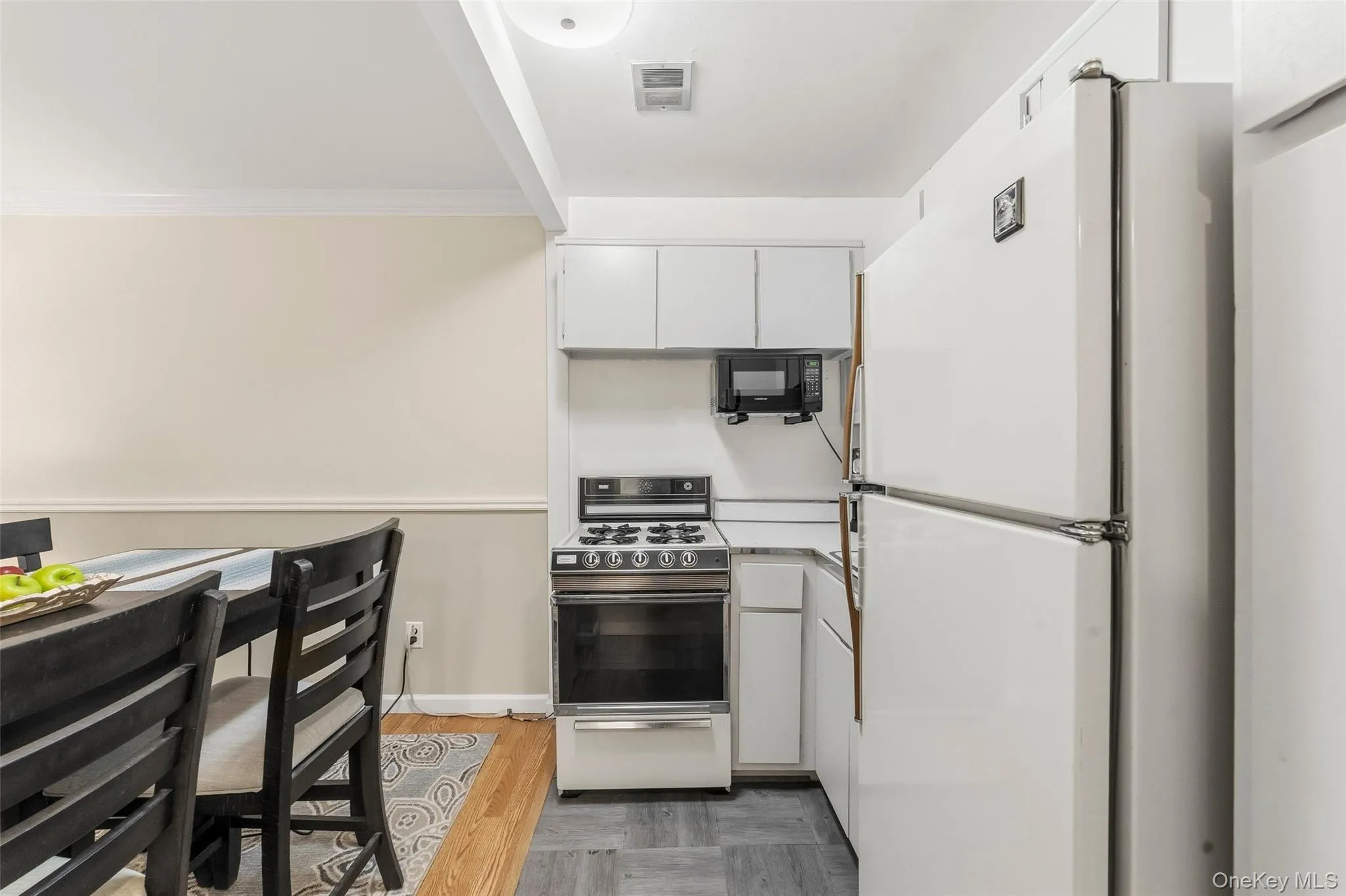 Compact kitchen featuring white cabinetry, a white refrigerator, a stove/oven. Compact kitchen featuring white cabinetry, a white refrigerator, a stove/oven.