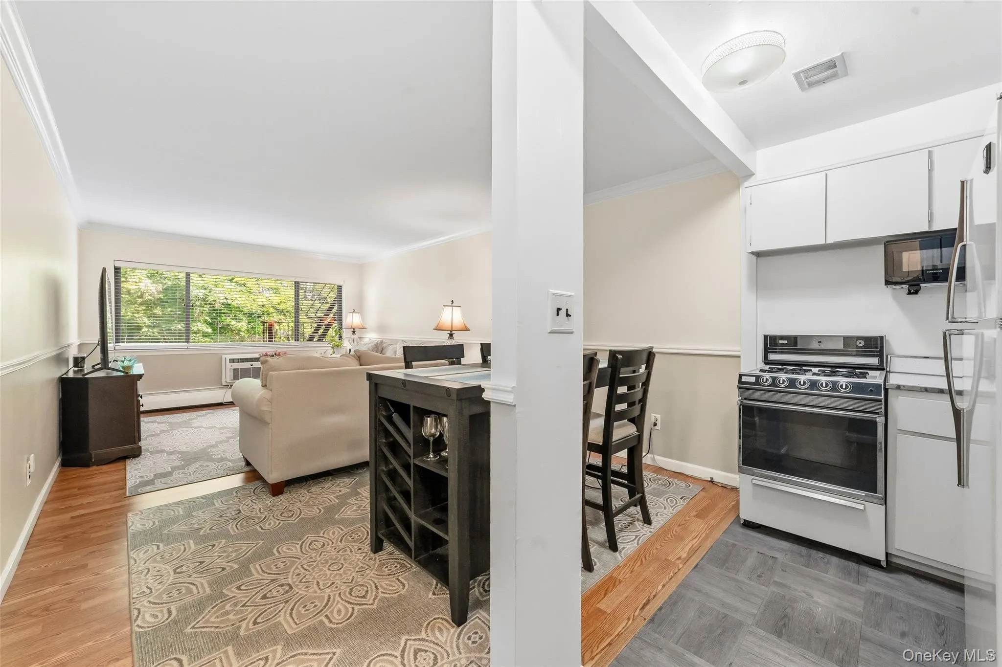 Open concept living space featuring a dedicated dining area, wood-finish flooring, crown molding, and large windows Open concept living space featuring a dedicated dining area, wood-finish flooring, crown molding, and large windows