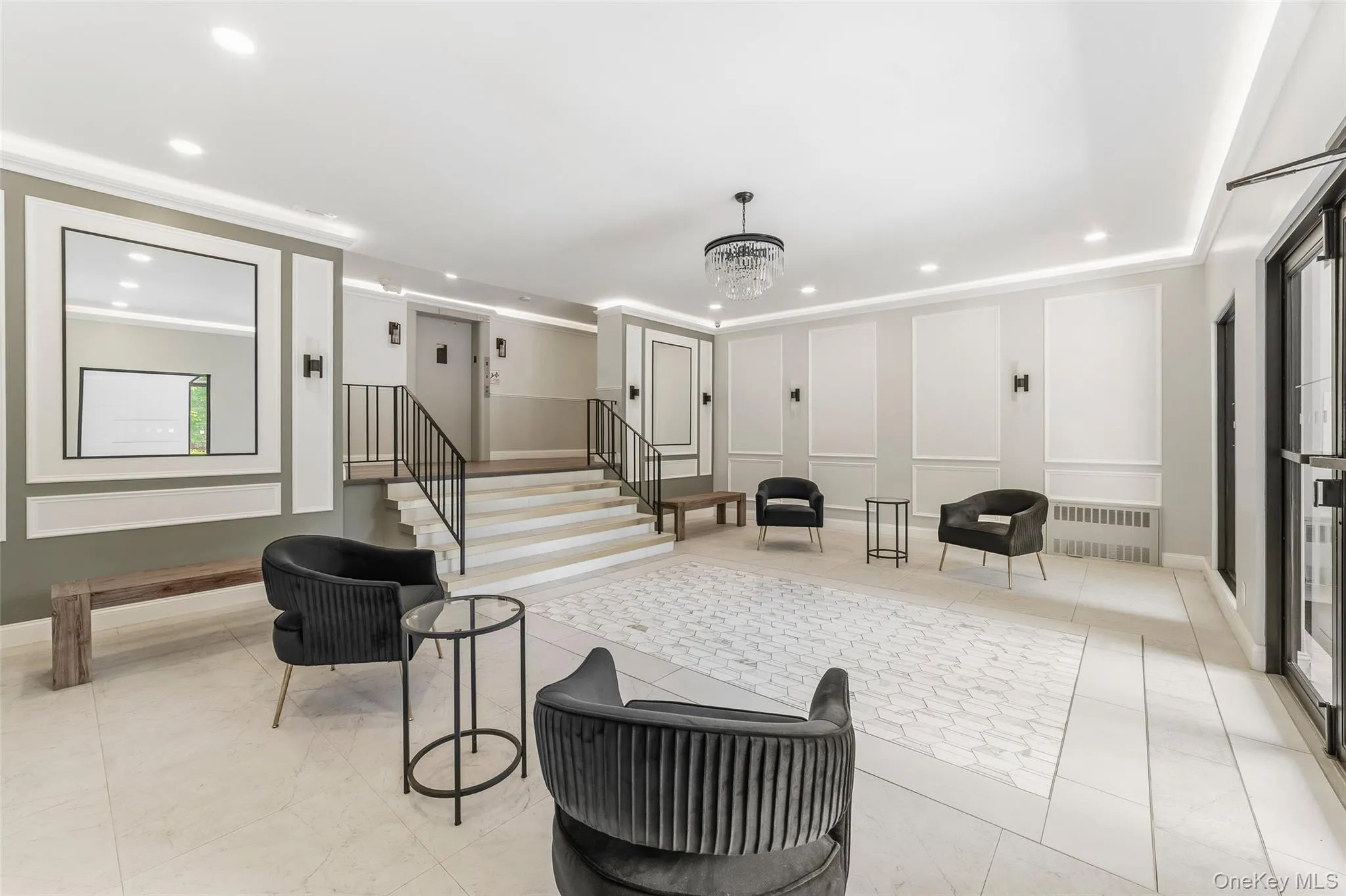 Spacious lobby featuring wainscoting and crown molding, a central chandelier, recessed lighting, and a combination of large format and hexagonal floor tiles Spacious lobby featuring wainscoting and crown molding, a central chandelier, recessed lighting, and a combination of large format and hexagonal floor tiles