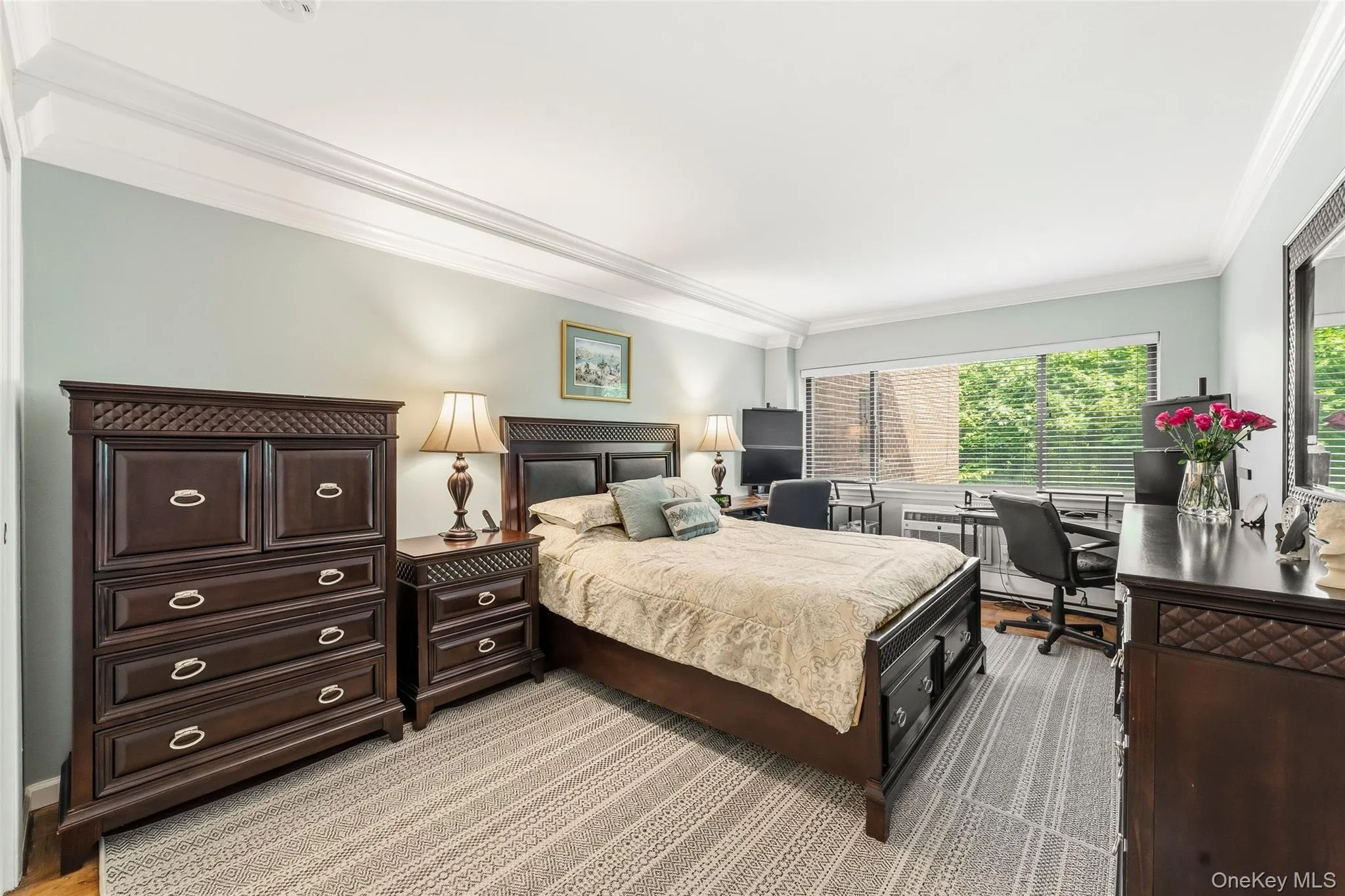 Spacious room featuring wood-finish flooring, a large window with horizontal blinds, and crown molding Spacious room featuring wood-finish flooring, a large window with horizontal blinds, and crown molding