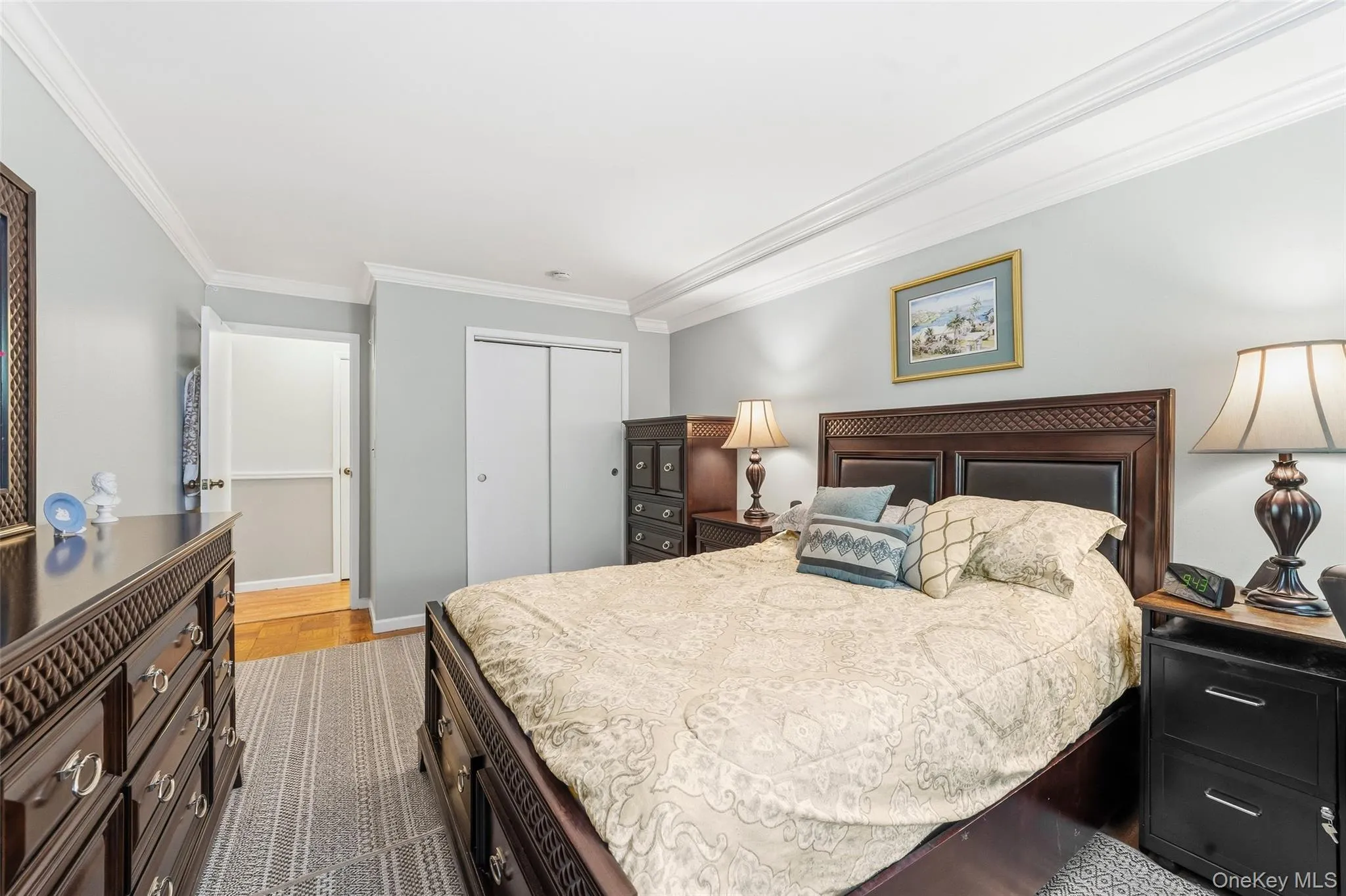 Bedroom featuring crown molding, a built-in closet with bi-fold doors, and a wood-finish floor entry Bedroom featuring crown molding, a built-in closet with bi-fold doors, and a wood-finish floor entry