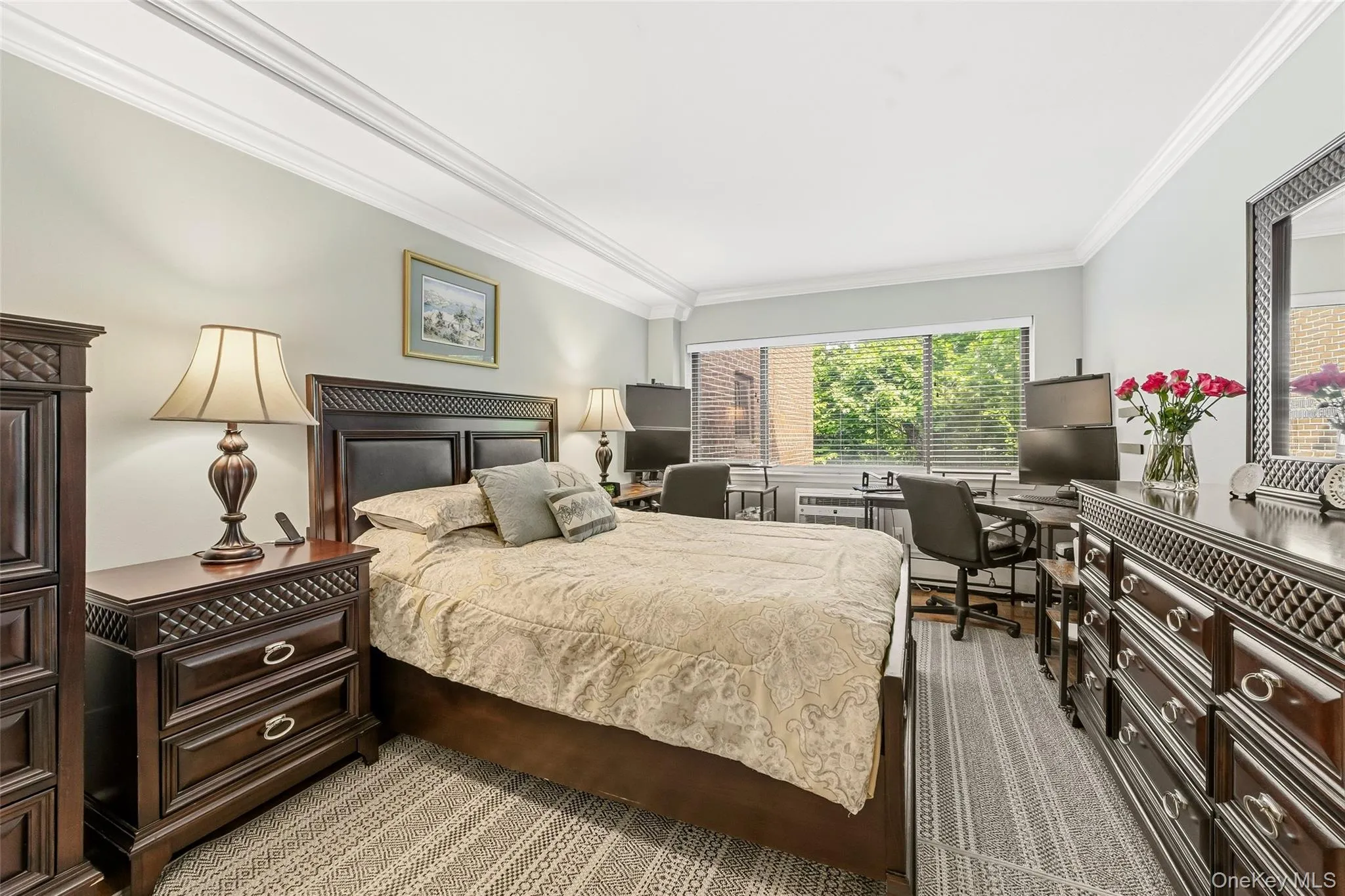 Bedroom featuring light gray wall paint, crown molding, a large window with horizontal blinds, and a textured area rug Bedroom featuring light gray wall paint, crown molding, a large window with horizontal blinds, and a textured area rug