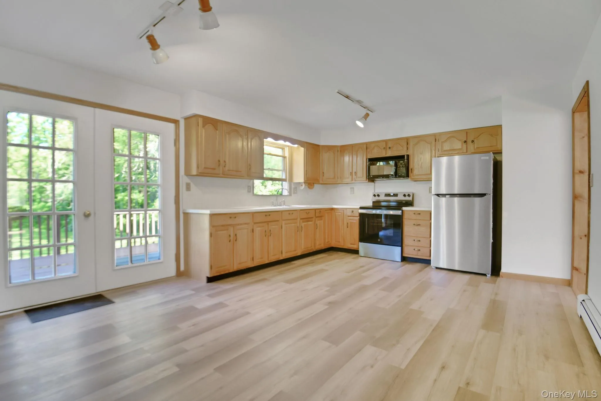 Kitchen featuring light wood-finish flooring, light wood cabinetry, white countertops, and stainless steel appliances Kitchen featuring light wood-finish flooring, light wood cabinetry, white countertops, and stainless steel appliances