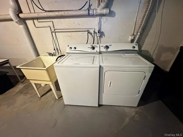 Laundry area featuring a side-by-side washer and dryer set, a utility sink, and concrete flooring Laundry area featuring a side-by-side washer and dryer set, a utility sink, and concrete flooring