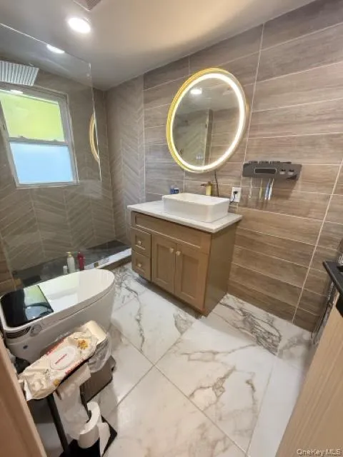 Bathroom featuring tile walls, vanity, light marble finish flooring, a walk in shower, and recessed lighting Bathroom featuring tile walls, vanity, light marble finish flooring, a walk in shower, and recessed lighting