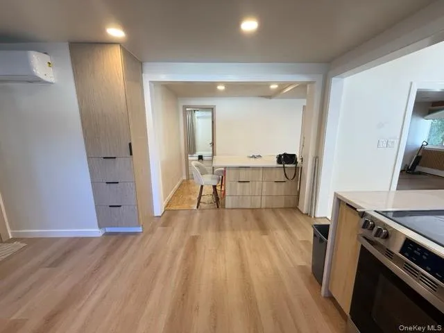 Kitchen with stainless steel electric range, light wood-type flooring, an AC wall unit, recessed lighting, and modern cabinets Kitchen with stainless steel electric range, light wood-type flooring, an AC wall unit, recessed lighting, and modern cabinets