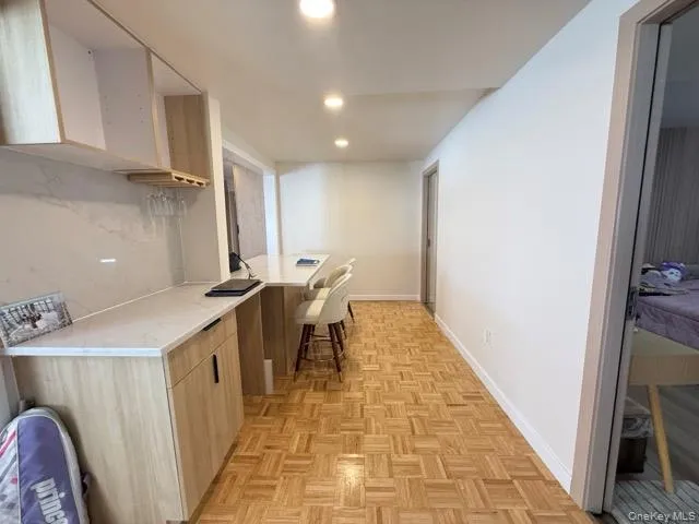 Kitchen with modern cabinets, light stone countertops, a peninsula, a kitchen bar, and recessed lighting Kitchen with modern cabinets, light stone countertops, a peninsula, a kitchen bar, and recessed lighting