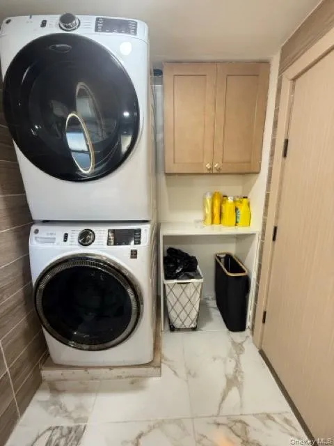 Laundry room with marble finish floors, stacked washer / drying machine, and cabinet space Laundry room with marble finish floors, stacked washer / drying machine, and cabinet space