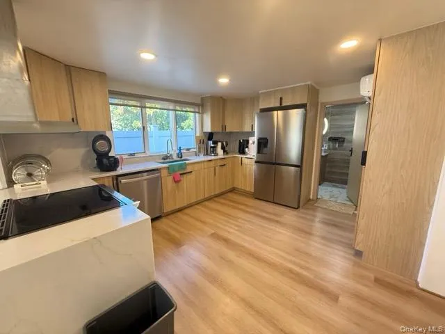 Kitchen with stainless steel appliances, light wood-style flooring, light stone counters, light brown cabinetry, and modern cabinets Kitchen with stainless steel appliances, light wood-style flooring, light stone counters, light brown cabinetry, and modern cabinets