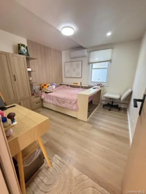 Bedroom with light wood-style floors and a wall mounted air conditioner Bedroom with light wood-style floors and a wall mounted air conditioner