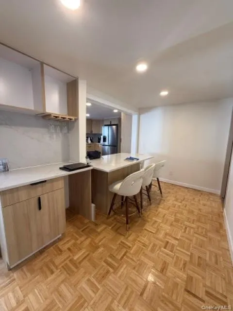 Kitchen featuring a peninsula, open shelves, modern cabinets, stainless steel refrigerator with ice dispenser, and a breakfast bar Kitchen featuring a peninsula, open shelves, modern cabinets, stainless steel refrigerator with ice dispenser, and a breakfast bar